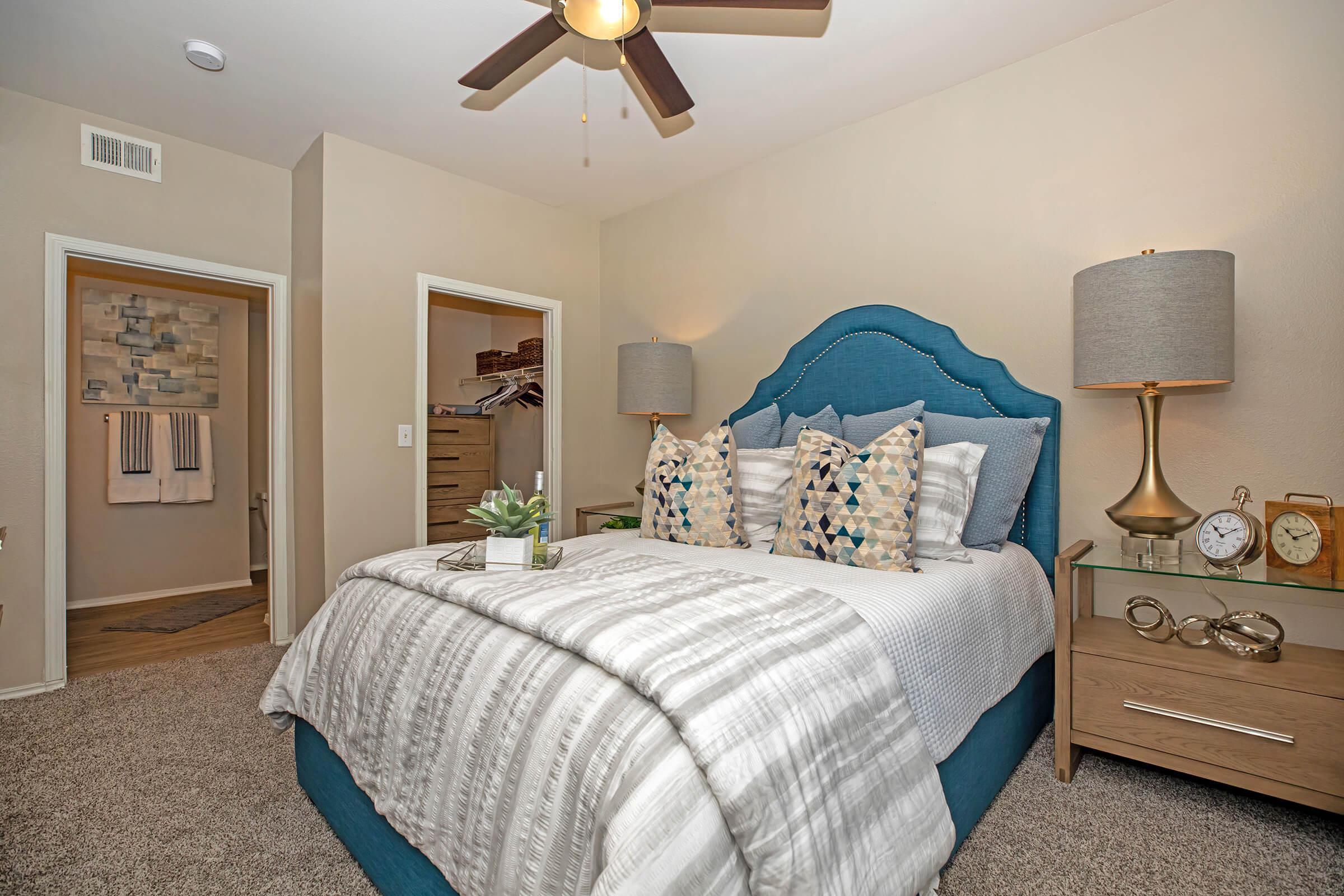 a furnished carpeted bedroom with attached walk-in closet