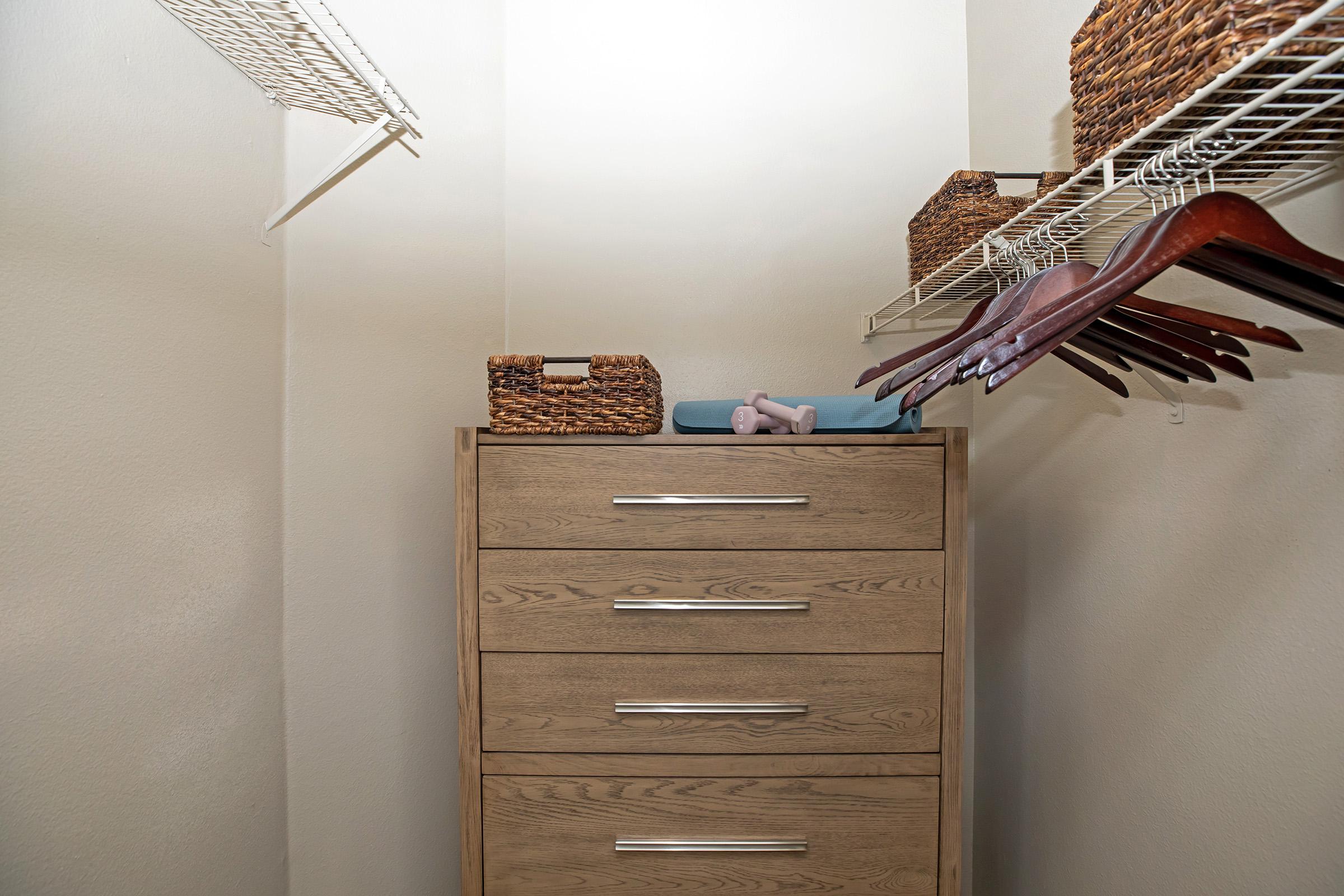 a furnished walk-in closet with a wooden dresser