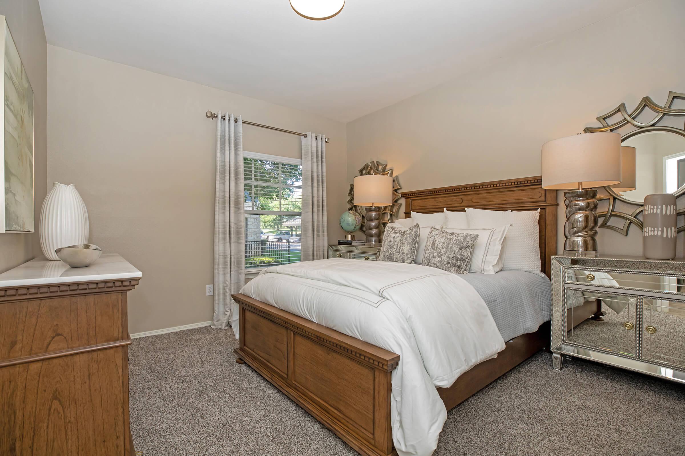 a furnished carpeted bedroom with a white comforter