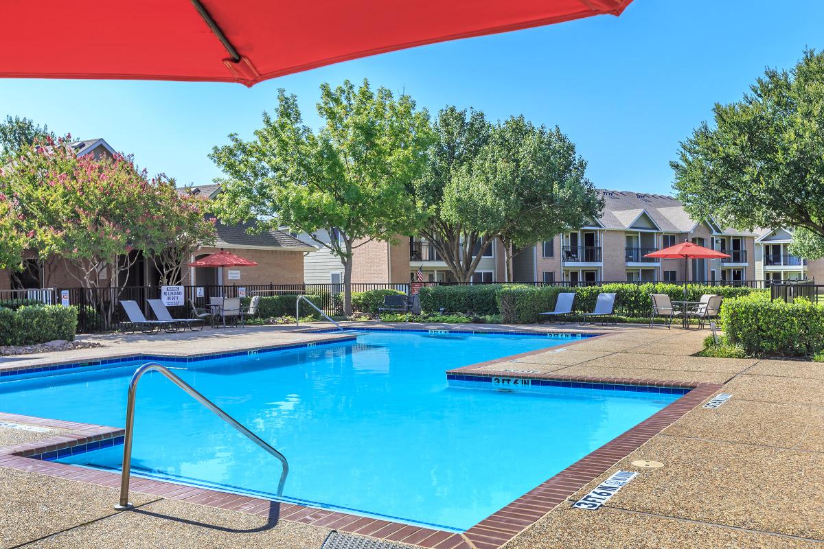 a red umbrella next to a pool of water