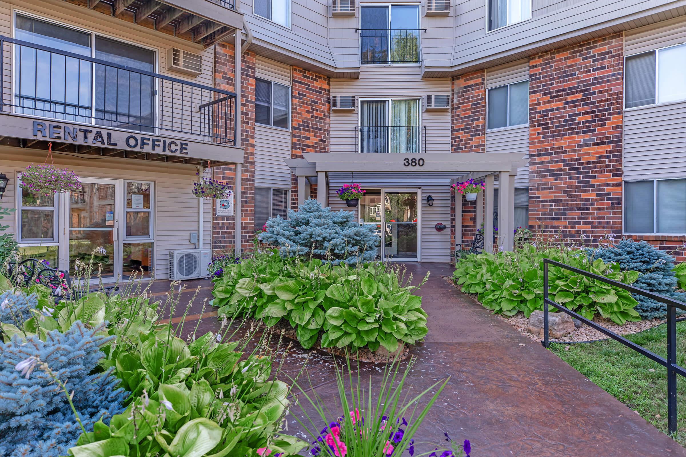 a close up of a flower garden in front of a brick building