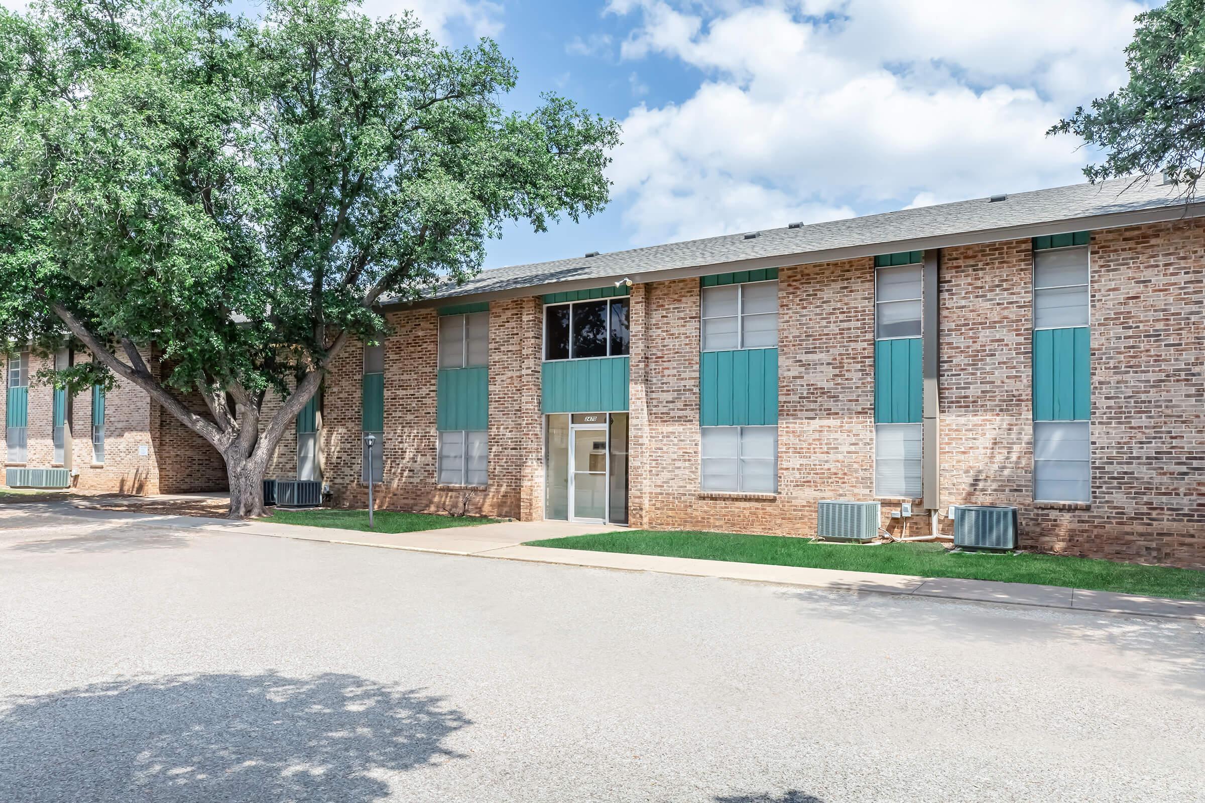 a dirt road in front of a brick building