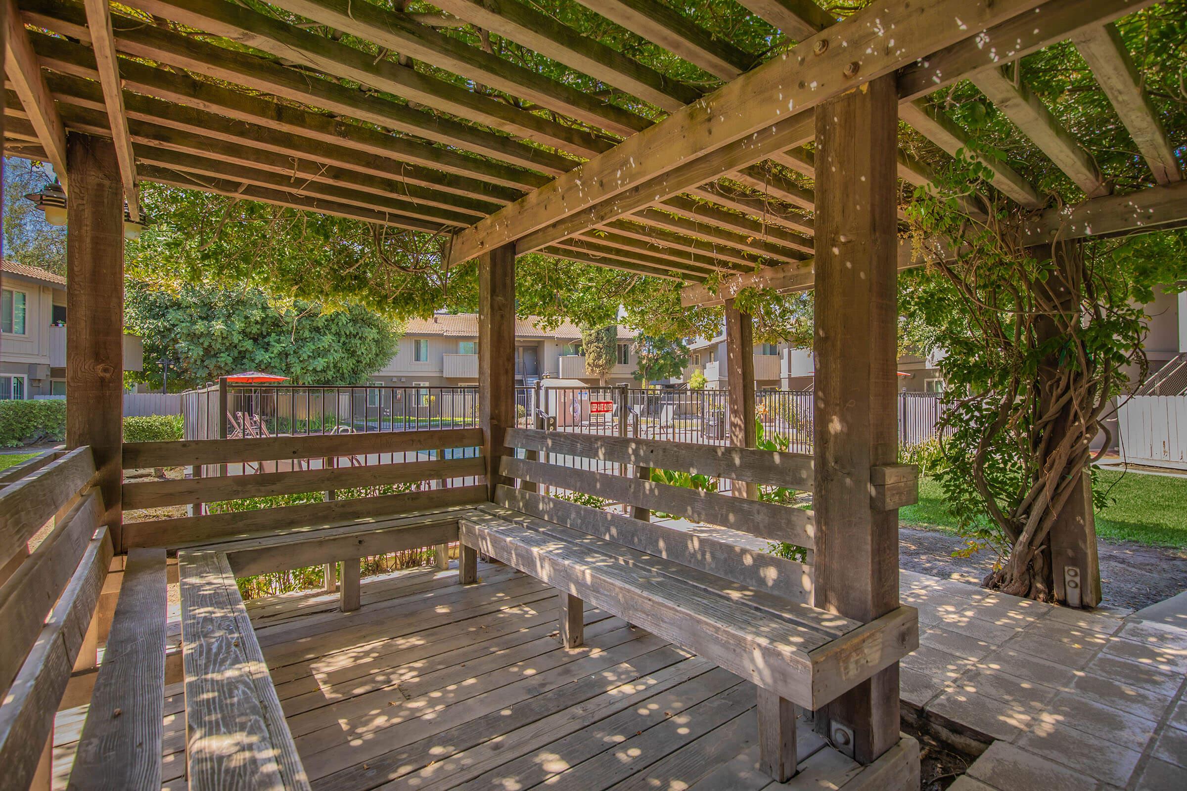 an empty park bench next to a fence