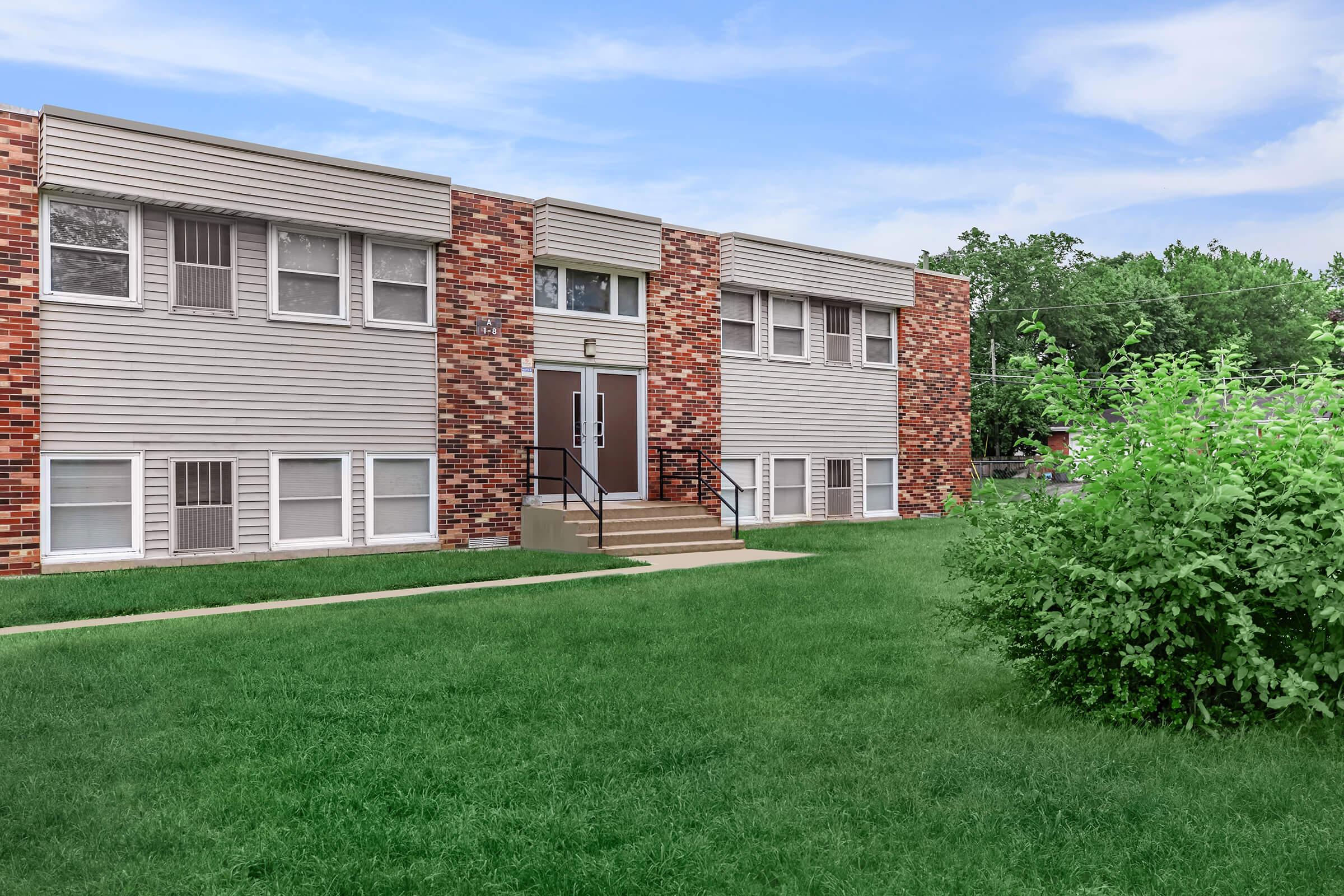 a large brick building with grass in front of a house