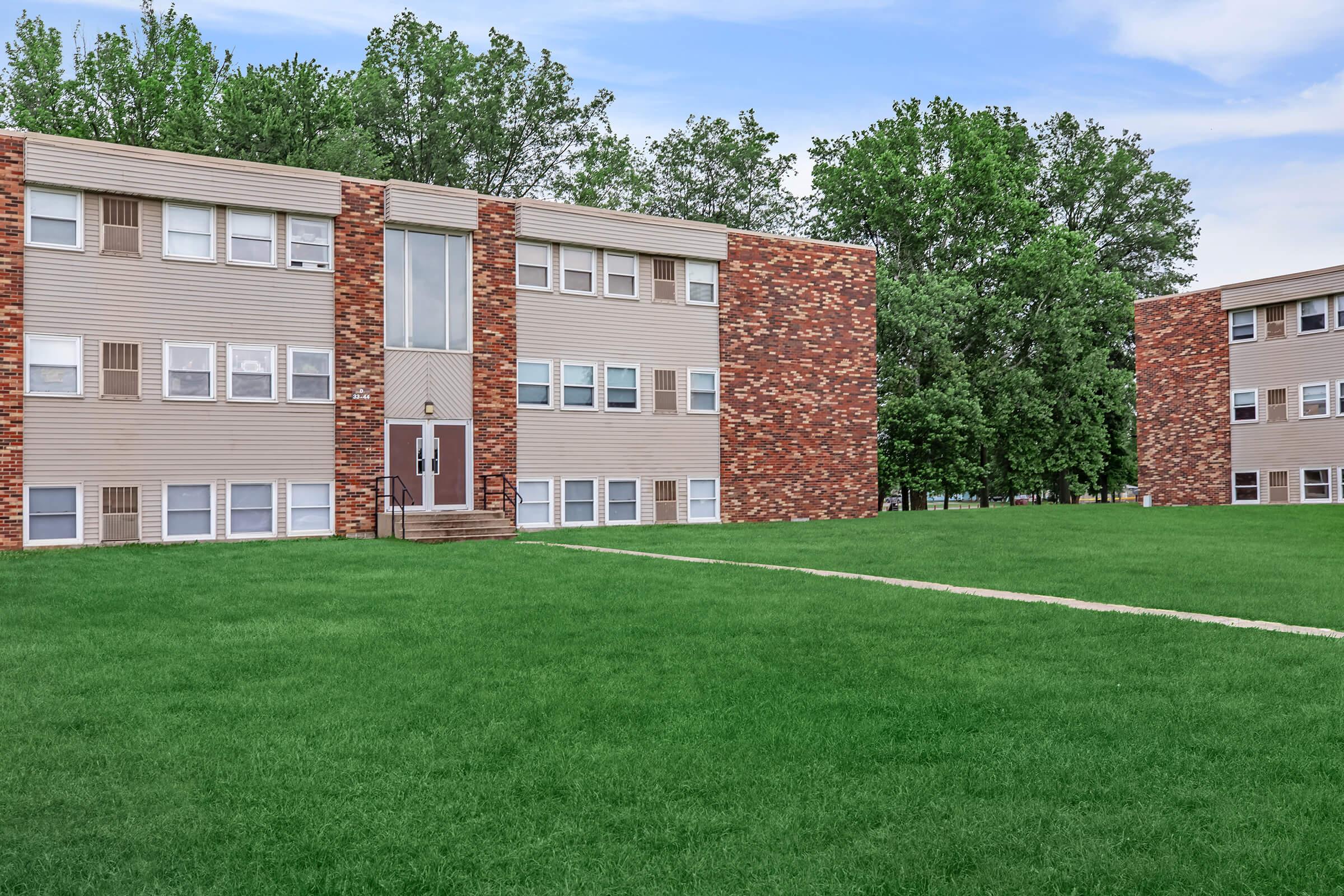 a large brick building with green grass in front of a house