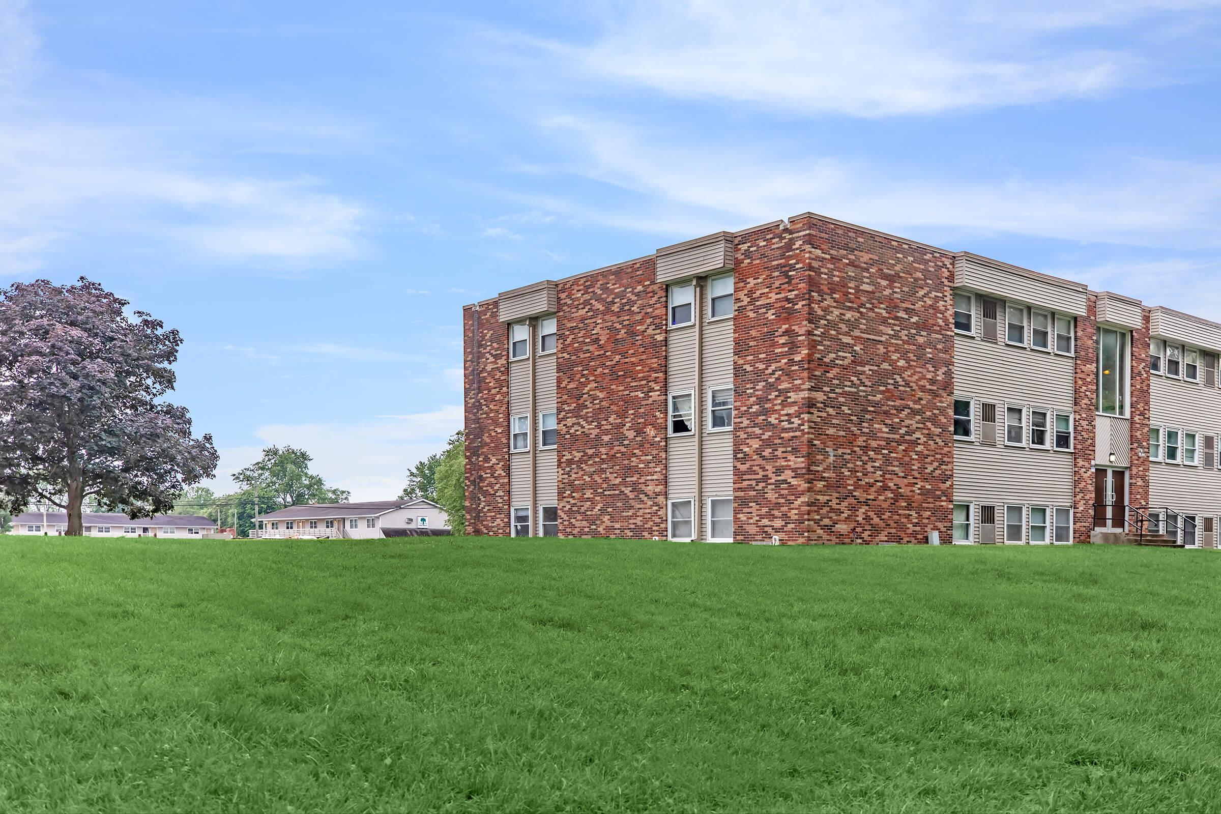 a large brick building with a grassy field