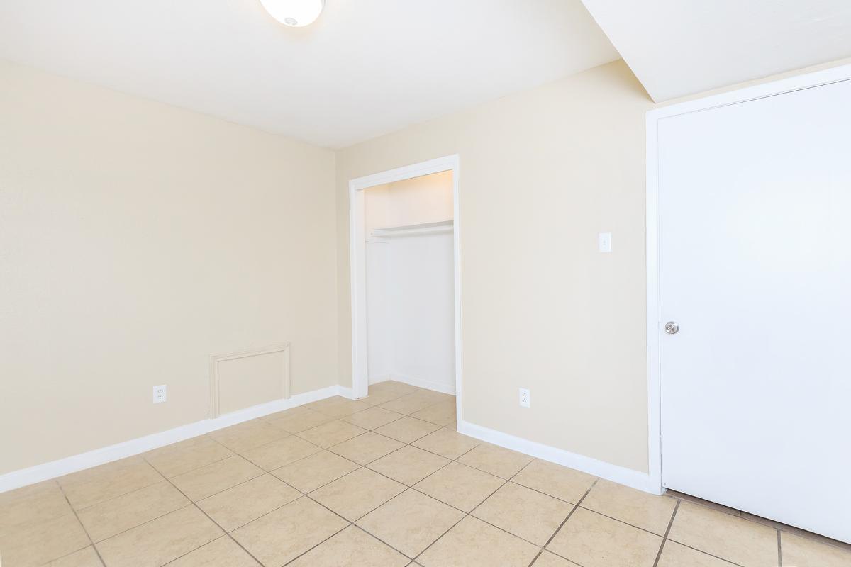 Bedroom with open closet door and tile floors