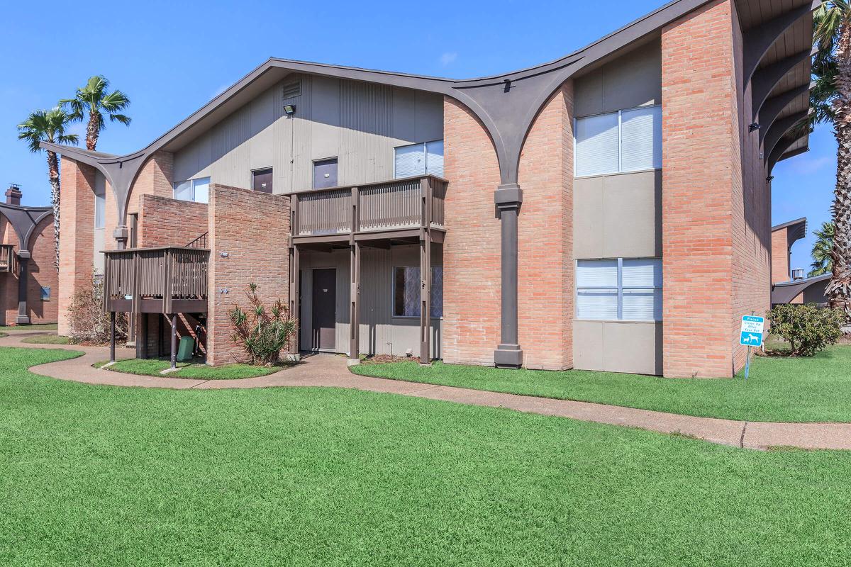 a large brick building with grass in front of a house