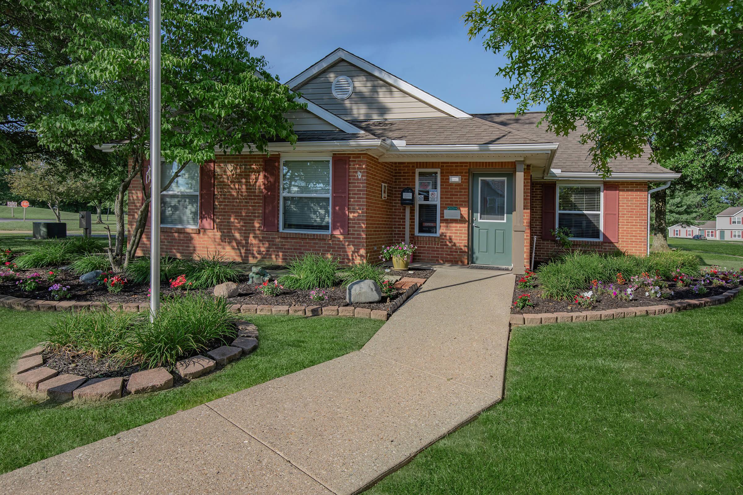 a house with a lawn in front of a brick building