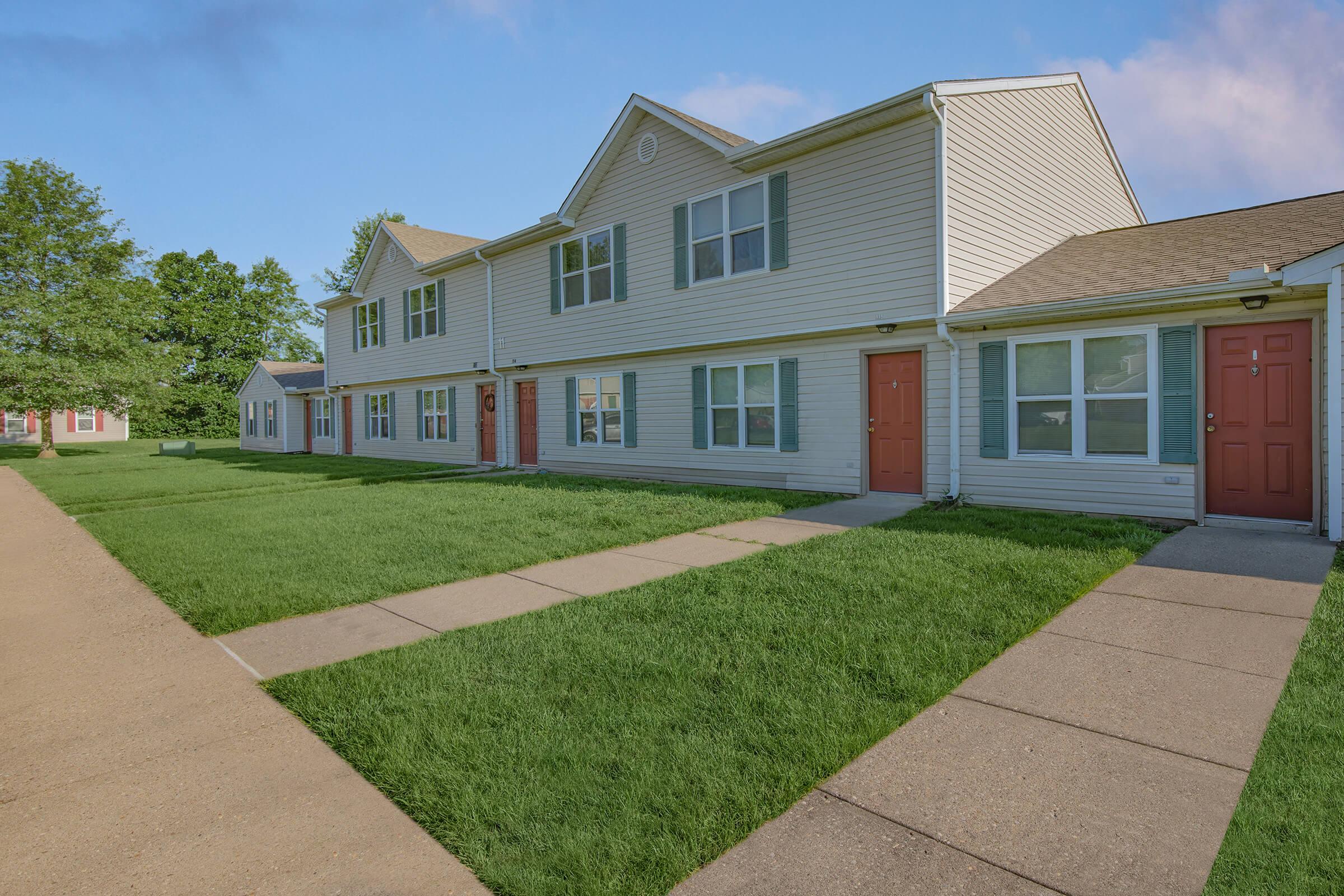 a large brick building with grass in front of a house