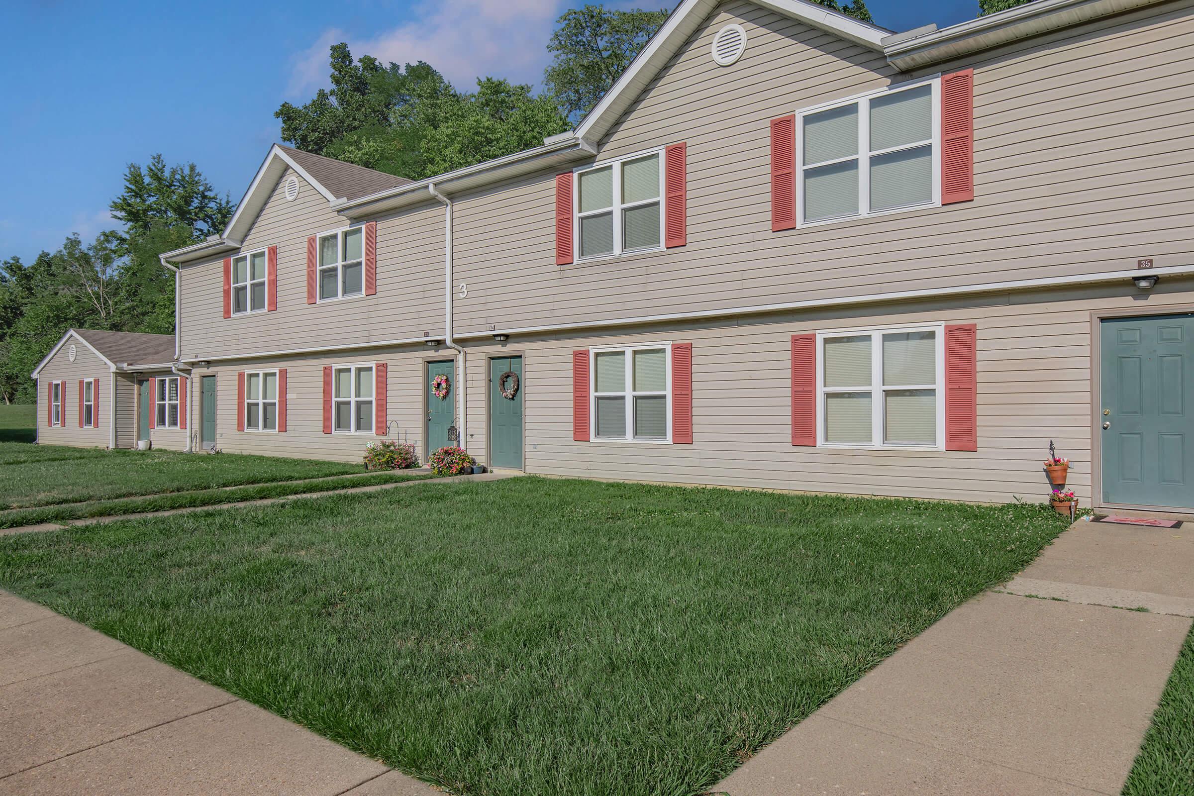 a large brick building with grass in front of a house