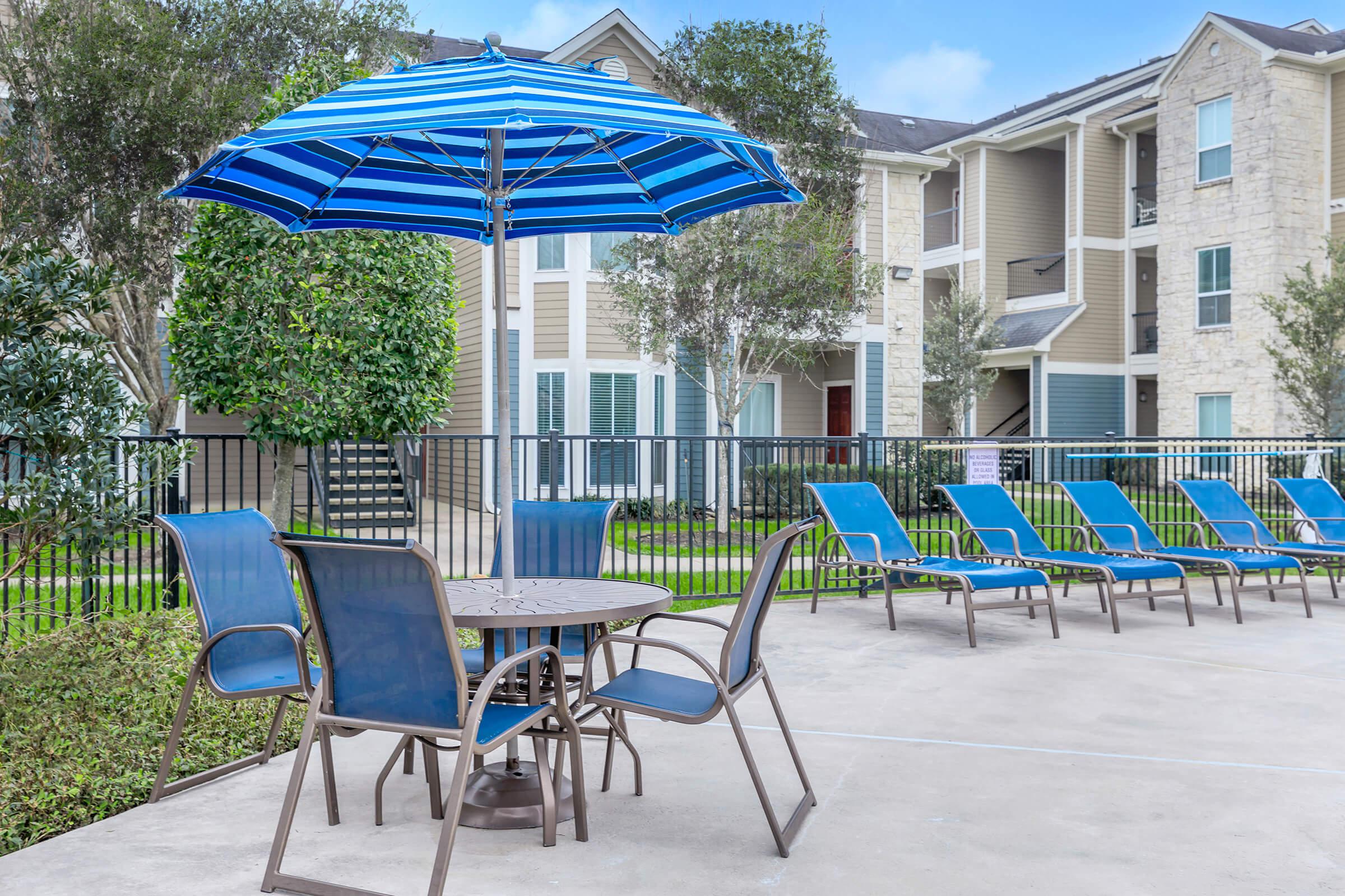 a couple of lawn chairs sitting on a chair with a blue umbrella