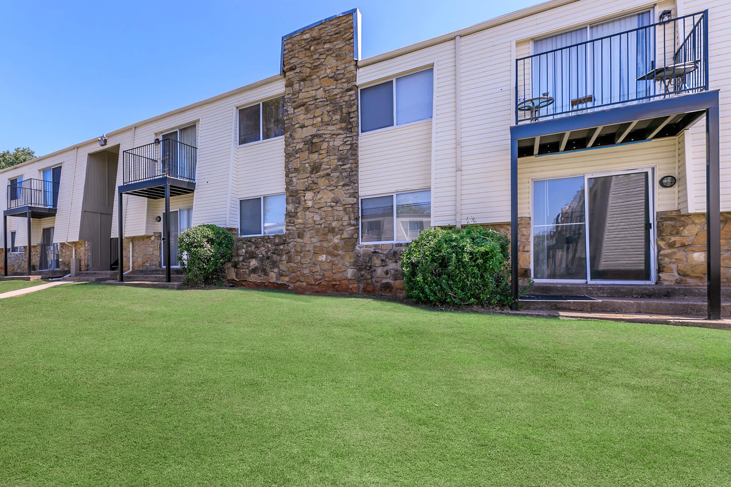 a large brick building with grass in front of a house