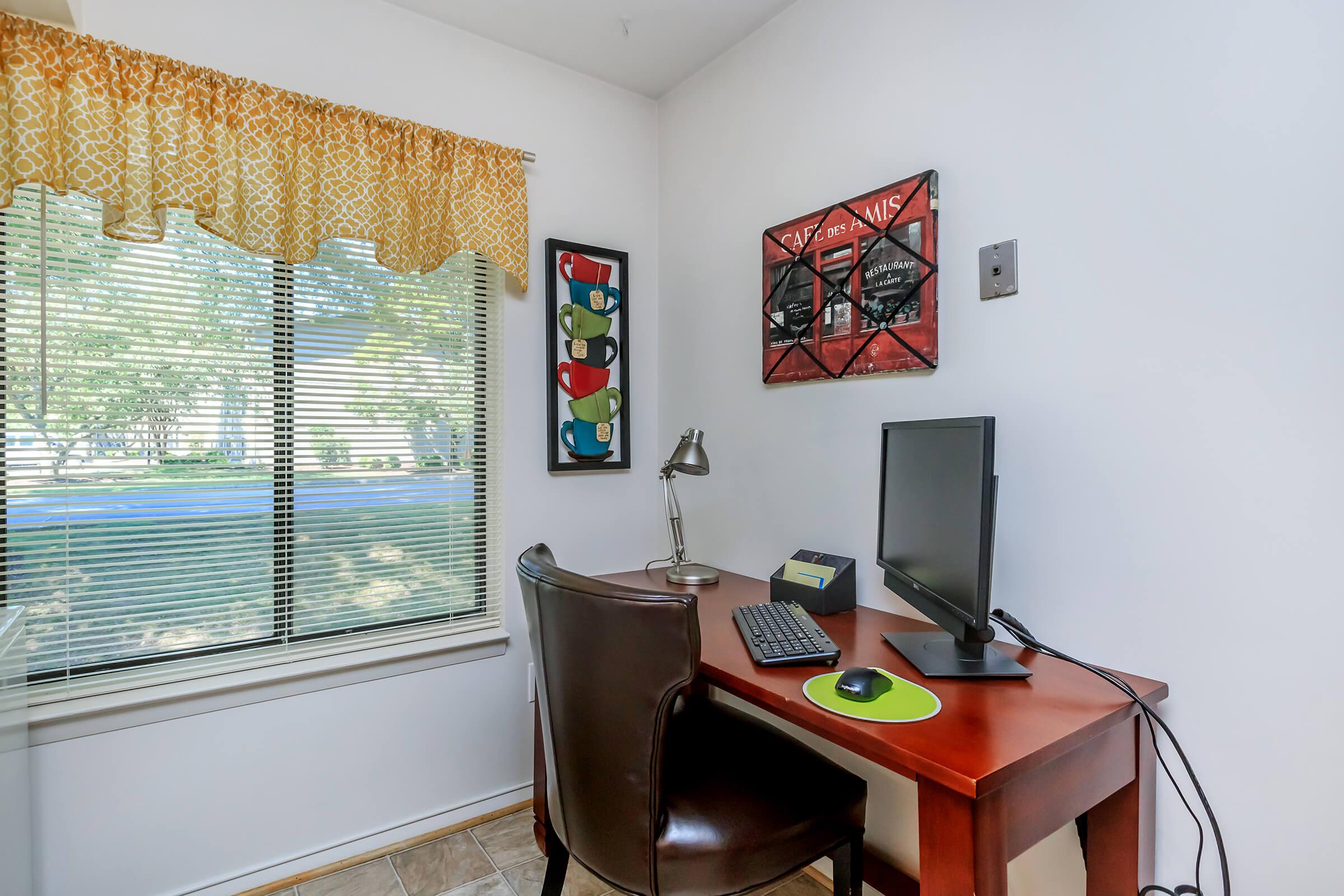 a desk with a computer and a chair in a room