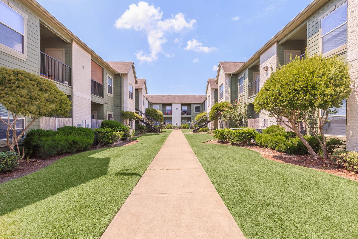 Central view of The Avenue apartment complex with spotless sidewalks and lush garden landscaping