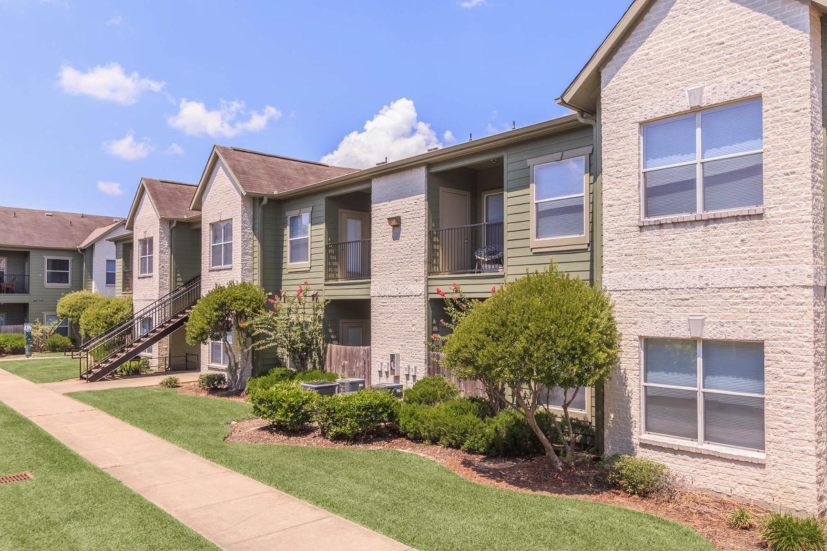 Exterior view of residential buildings with beautiful landscaped grounds at The Avenue apartments 