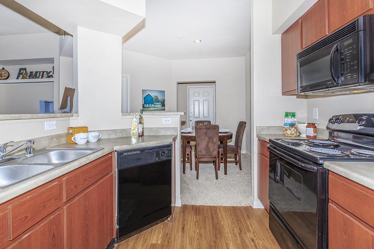 Kitchen with hardwood-style floors, black dishwasher and view of carpeted dining area