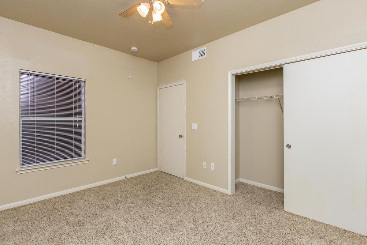 Bedroom with carpeted floors, walk-in closet, and ceiling fan 