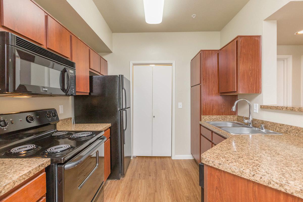 Galley-style kitchen with electric appliances and wood cabinets