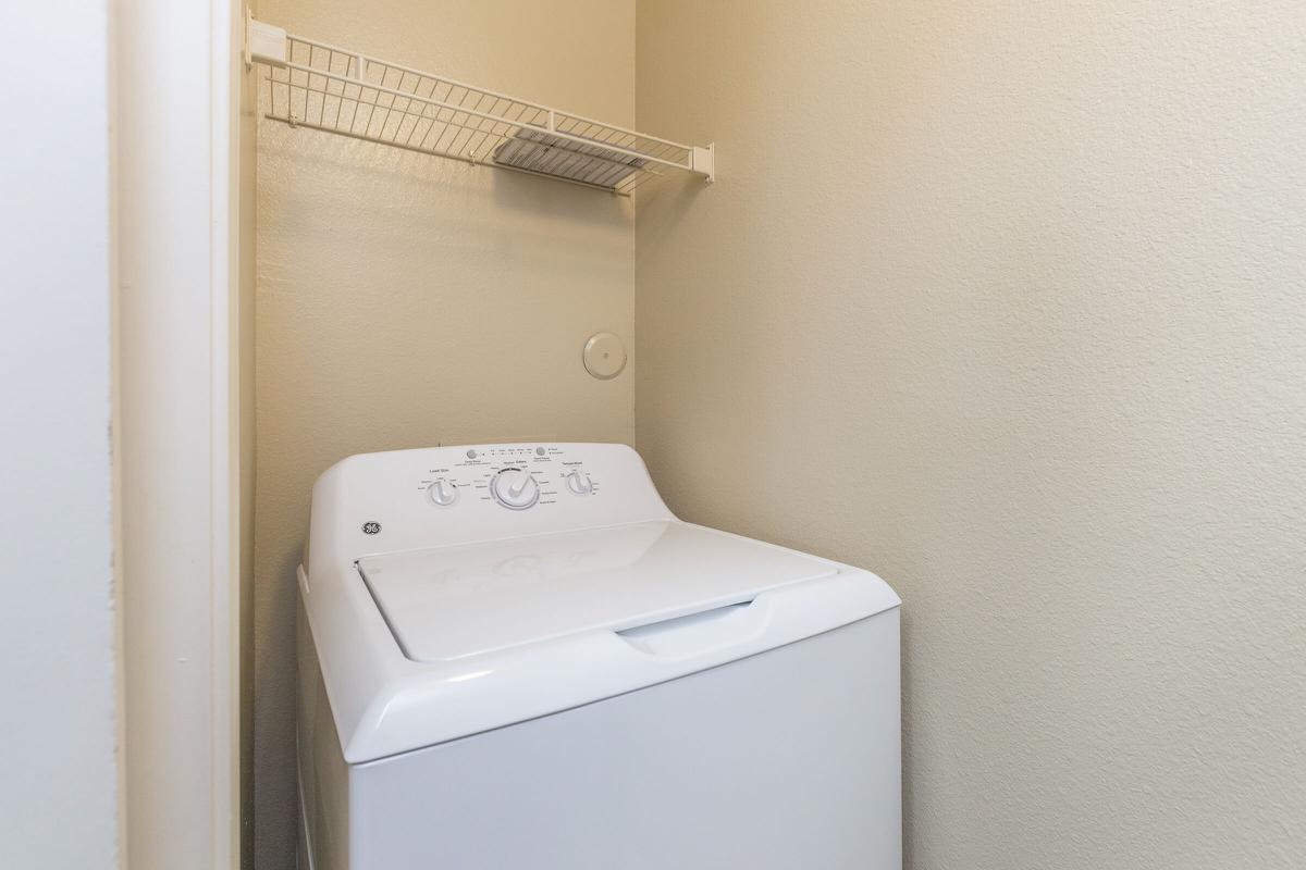 Laundry closet with full-size washer/dryer and shelf for extra storage 