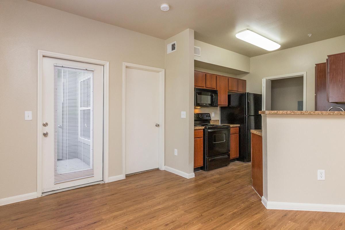 Living room with door to private balcony/patio and view of kitchen 