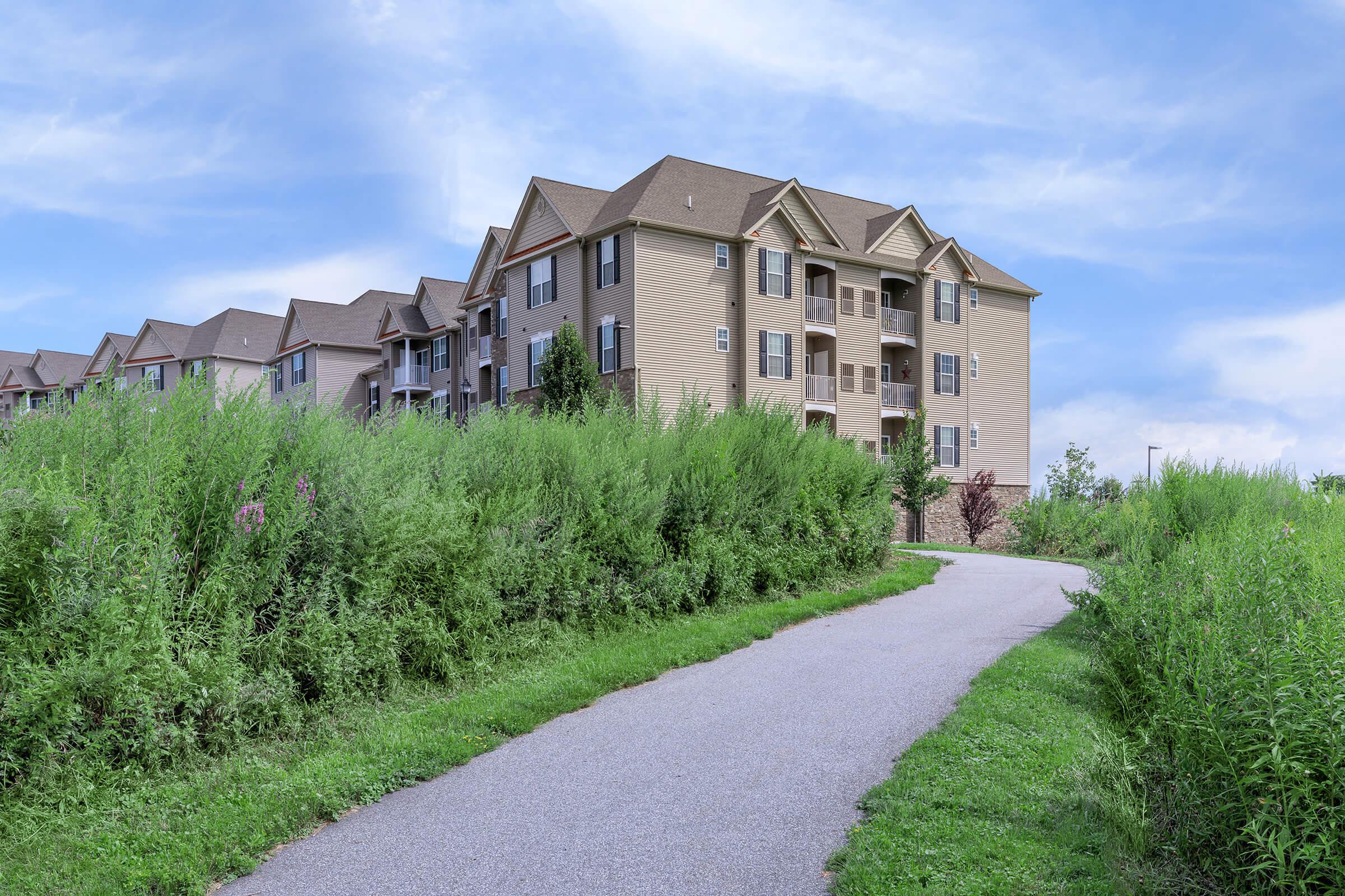 a path with grass in front of a brick building