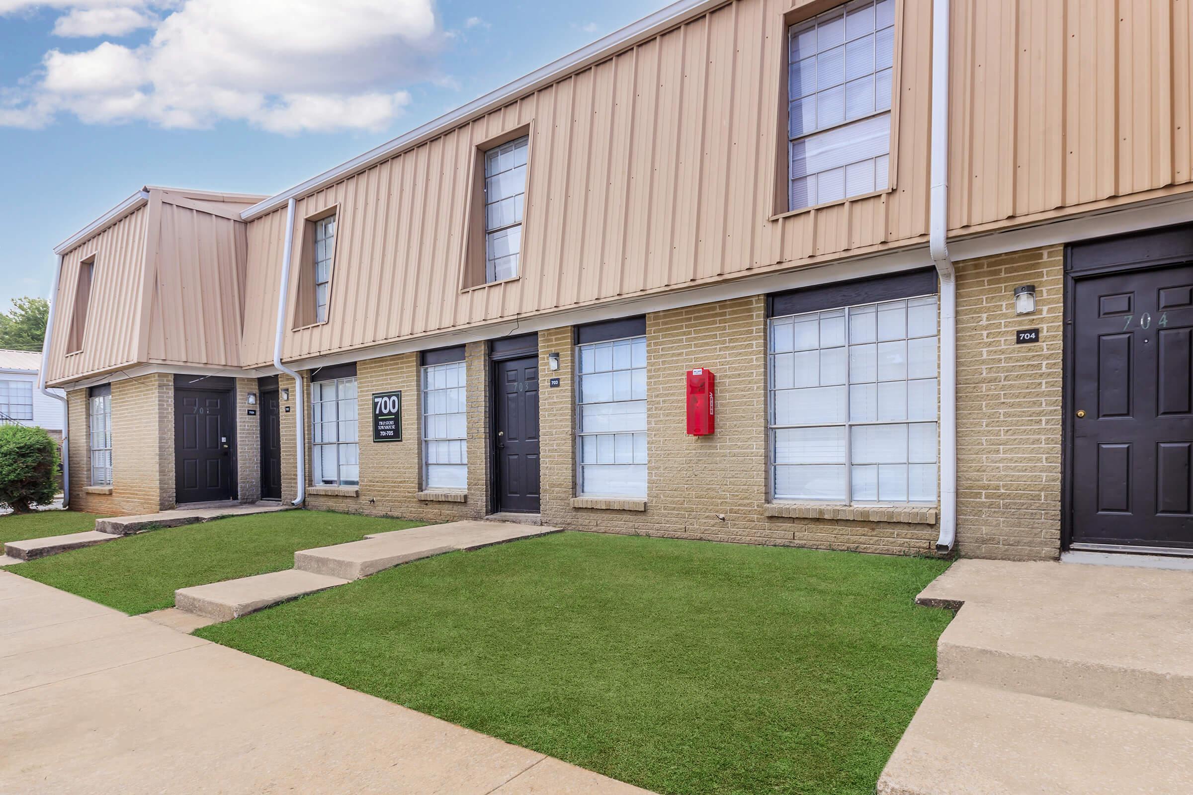 a large brick building with grass in front of a house