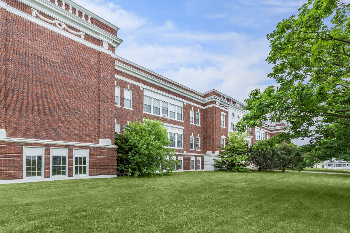 a large brick building with a grassy field