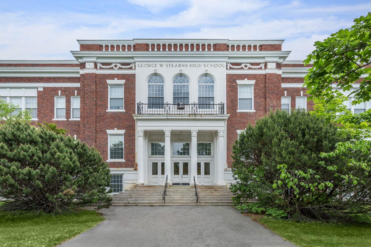 a large brick building with grass in front of a house