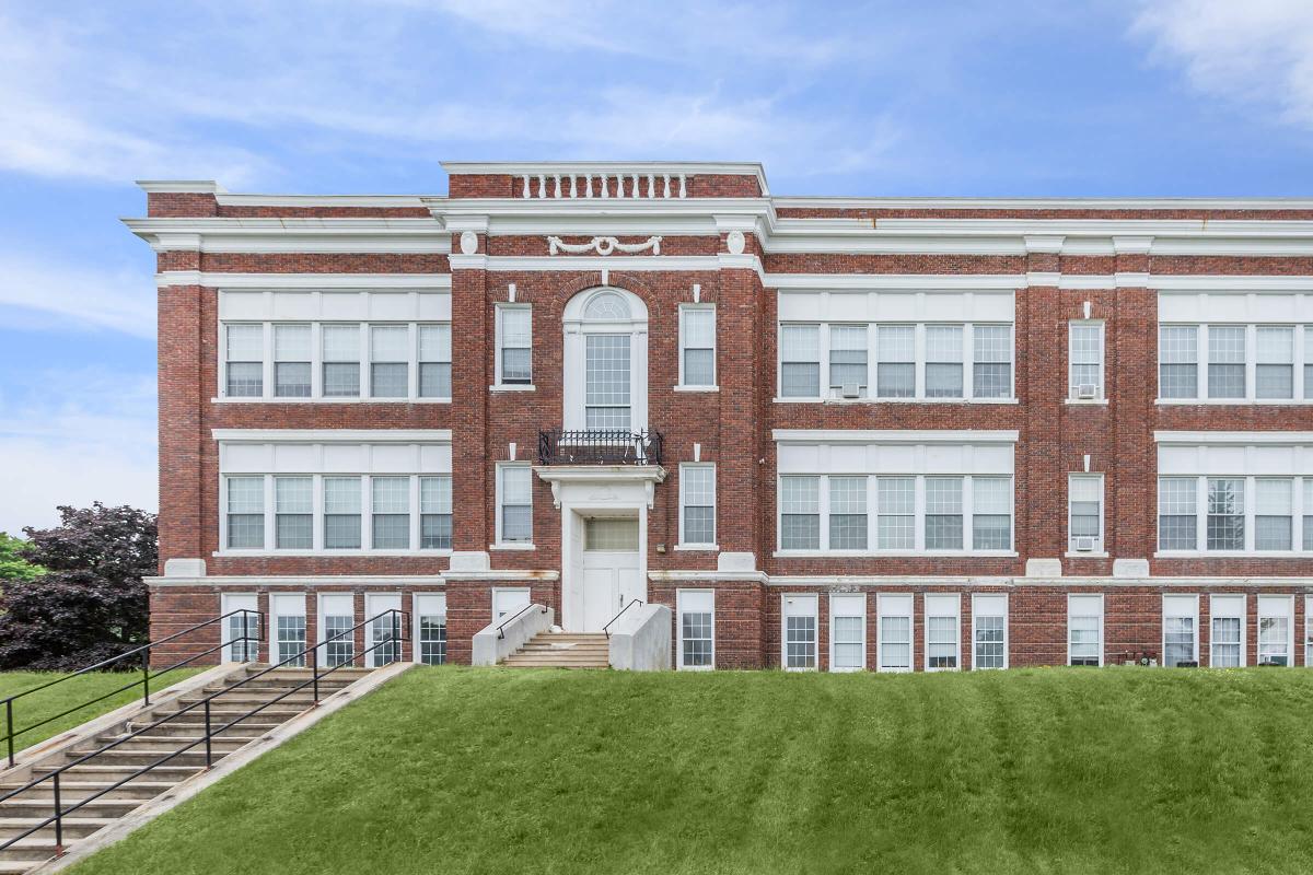 a large brick building with a grassy field