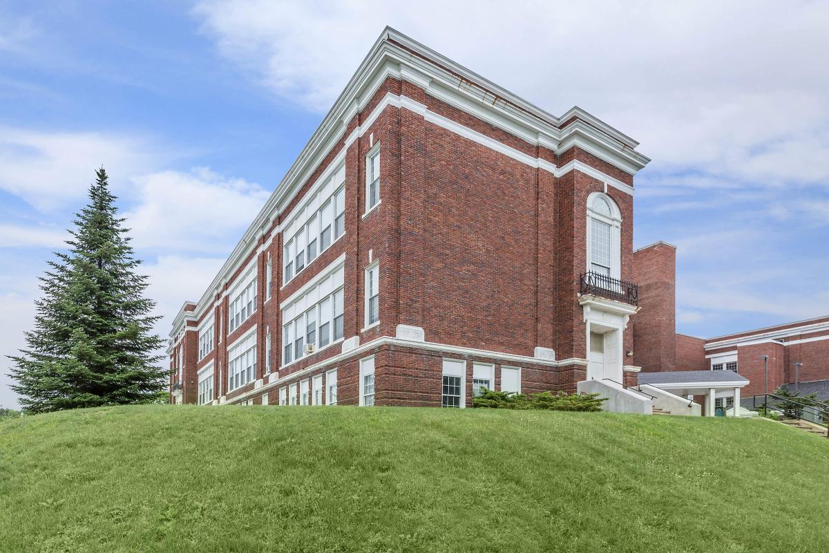 a large brick building with a grassy field