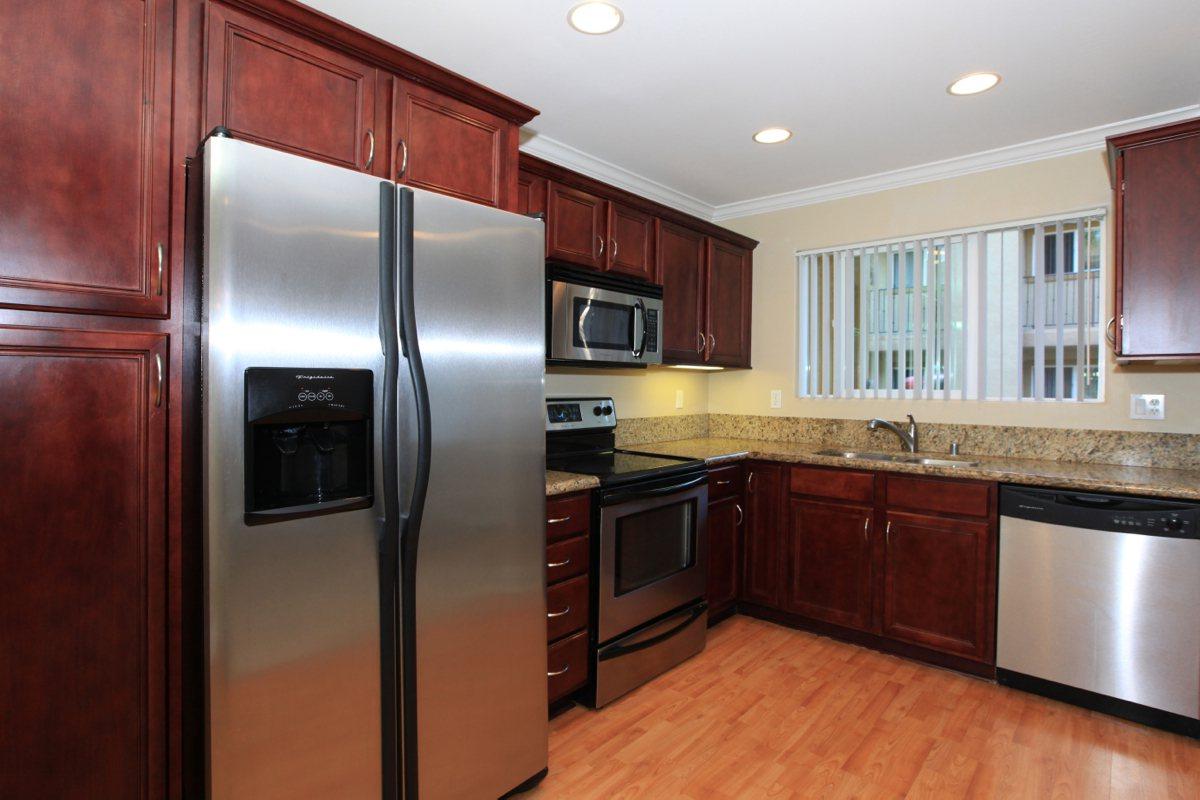 a large kitchen with stainless steel appliances and wooden cabinets