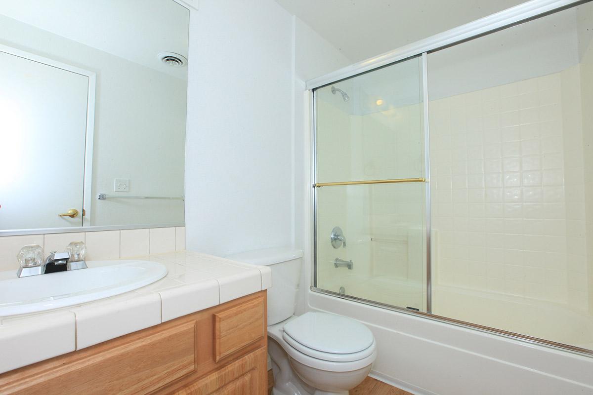 Hallway bathroom with single sink and tub with sliding shower doors