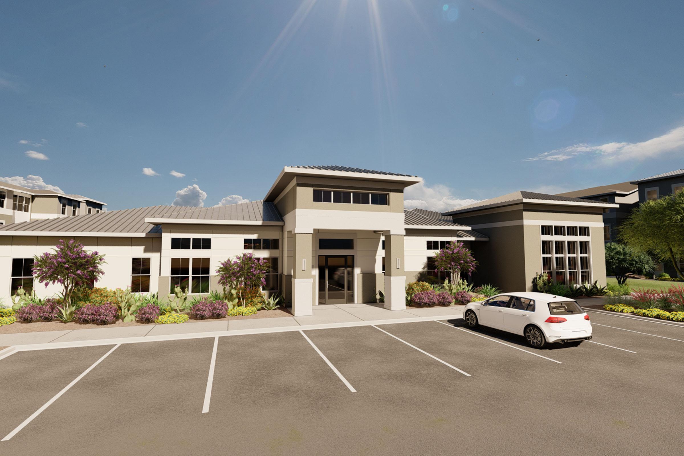 Modern building exterior with a sleek design, featuring a stone facade and large windows. Surrounded by landscaped gardens with colorful plants. A white car is parked in front of the entrance, and the sky is clear with bright sunlight illuminating the scene.