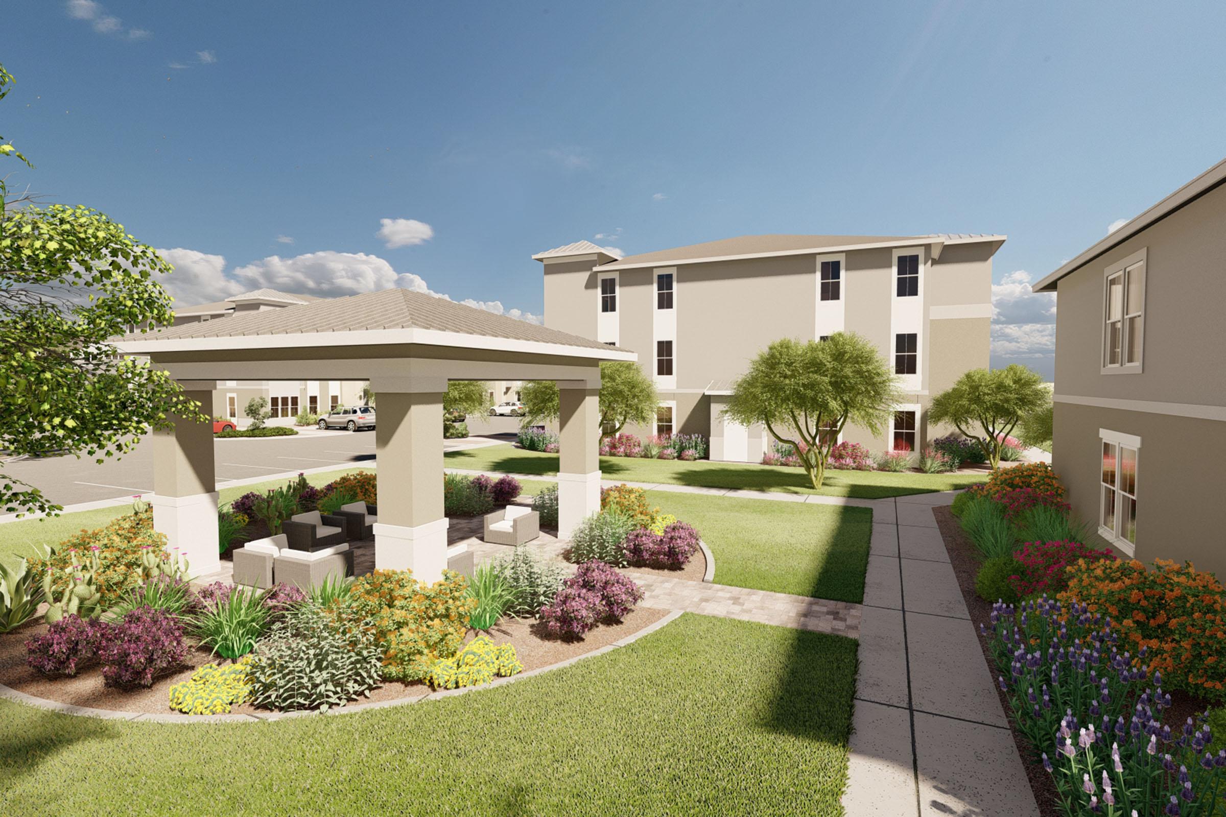 A landscaped outdoor area featuring a gazebo surrounded by colorful flower beds and greenery, leading to two multi-story buildings. The scene is bright and sunny with a blue sky and scattered clouds, creating a welcoming atmosphere for residents.