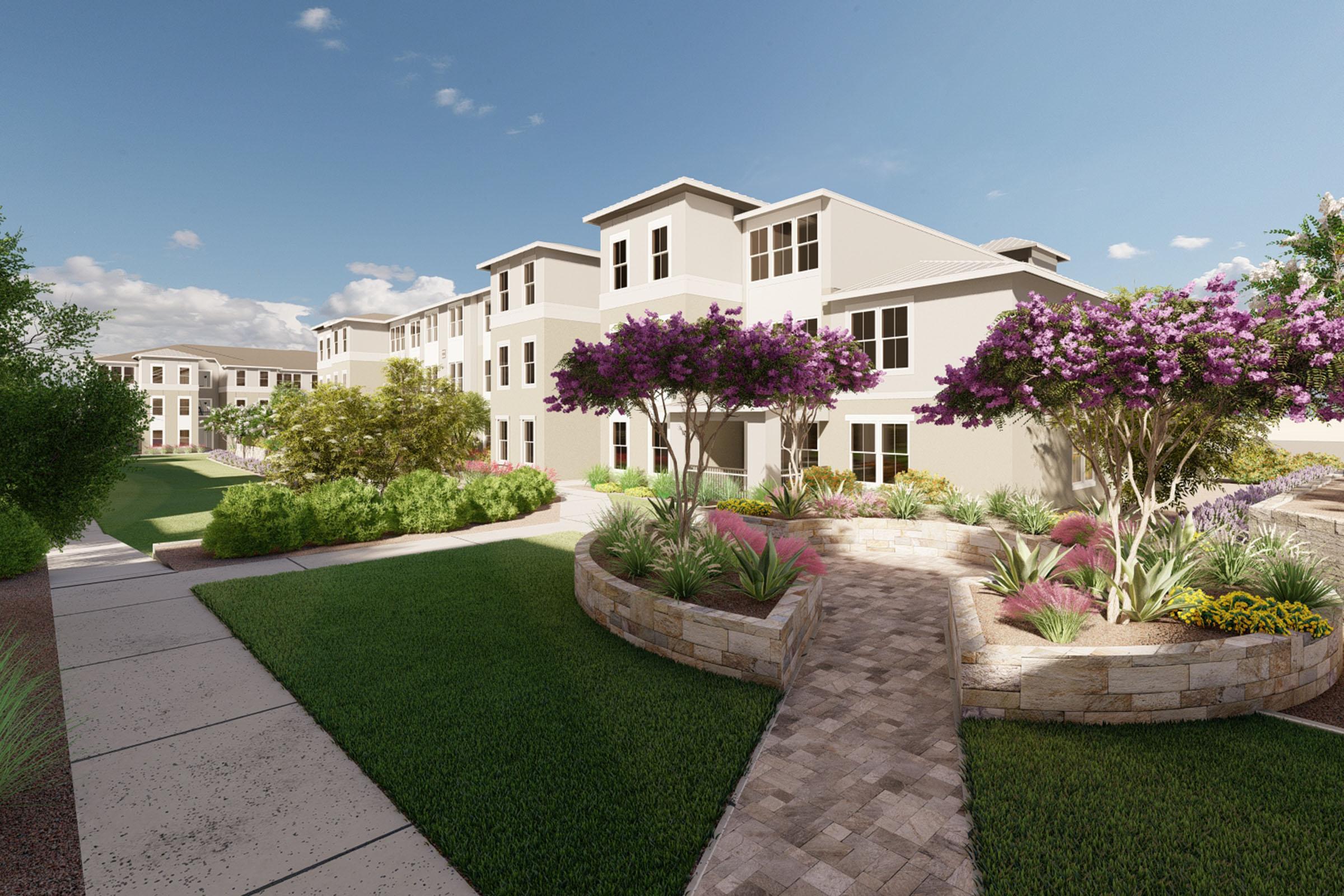 A scenic view of a modern residential building complex surrounded by lush greenery and vibrant purple flowers. A landscaped pathway leads through well-maintained gardens, with blue skies and fluffy clouds providing a bright, inviting atmosphere.
