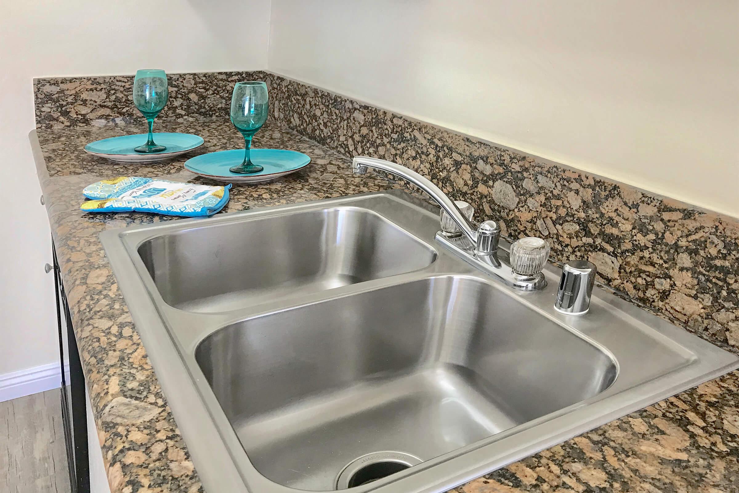Kitchen sink with two teal plates and glasses