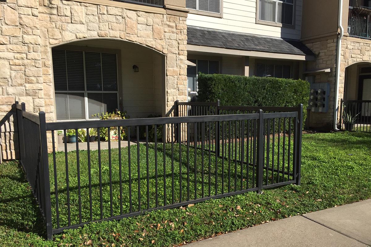 a house with a fence in front of a brick building