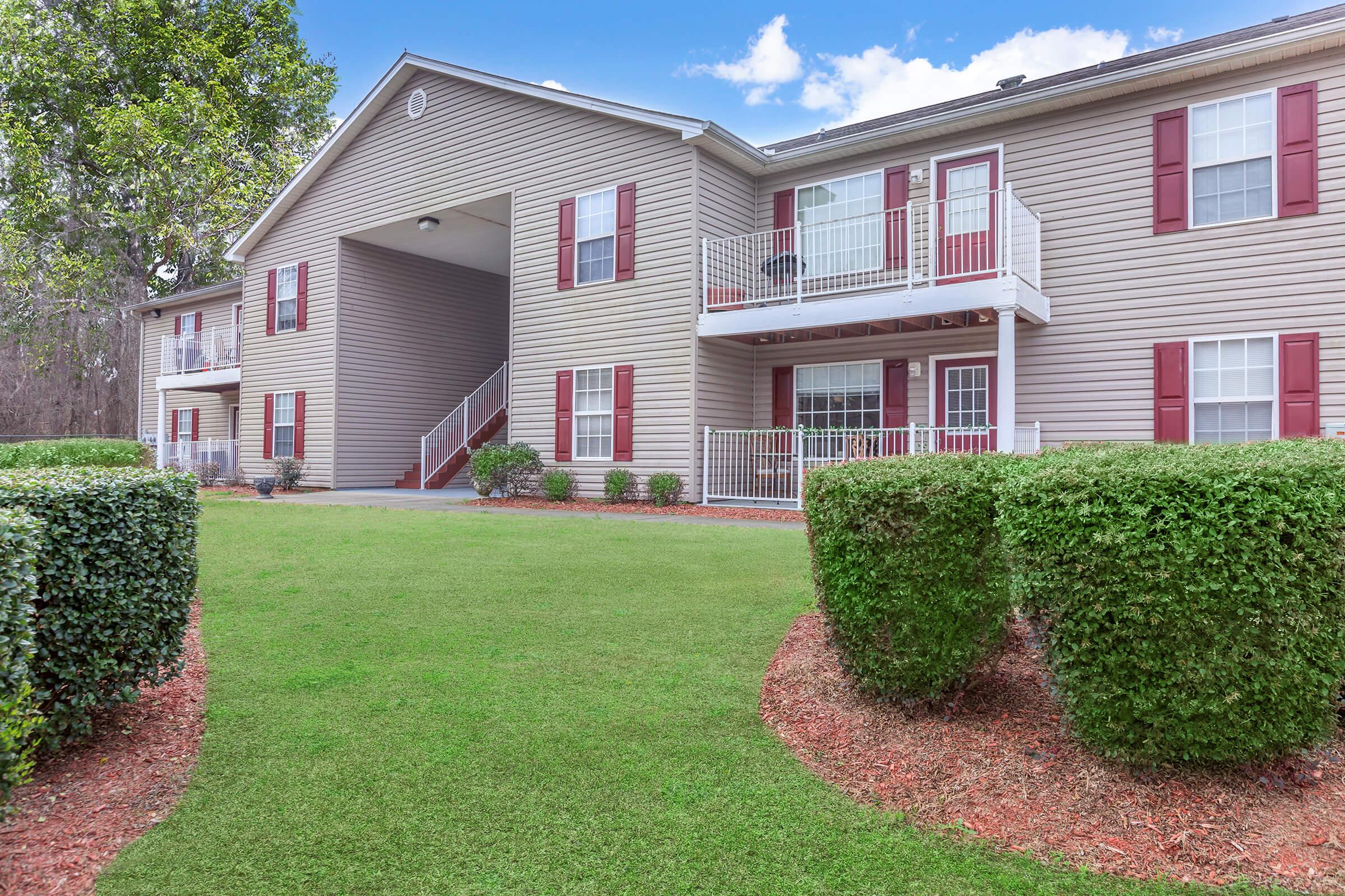 a large brick building with grass in front of a house