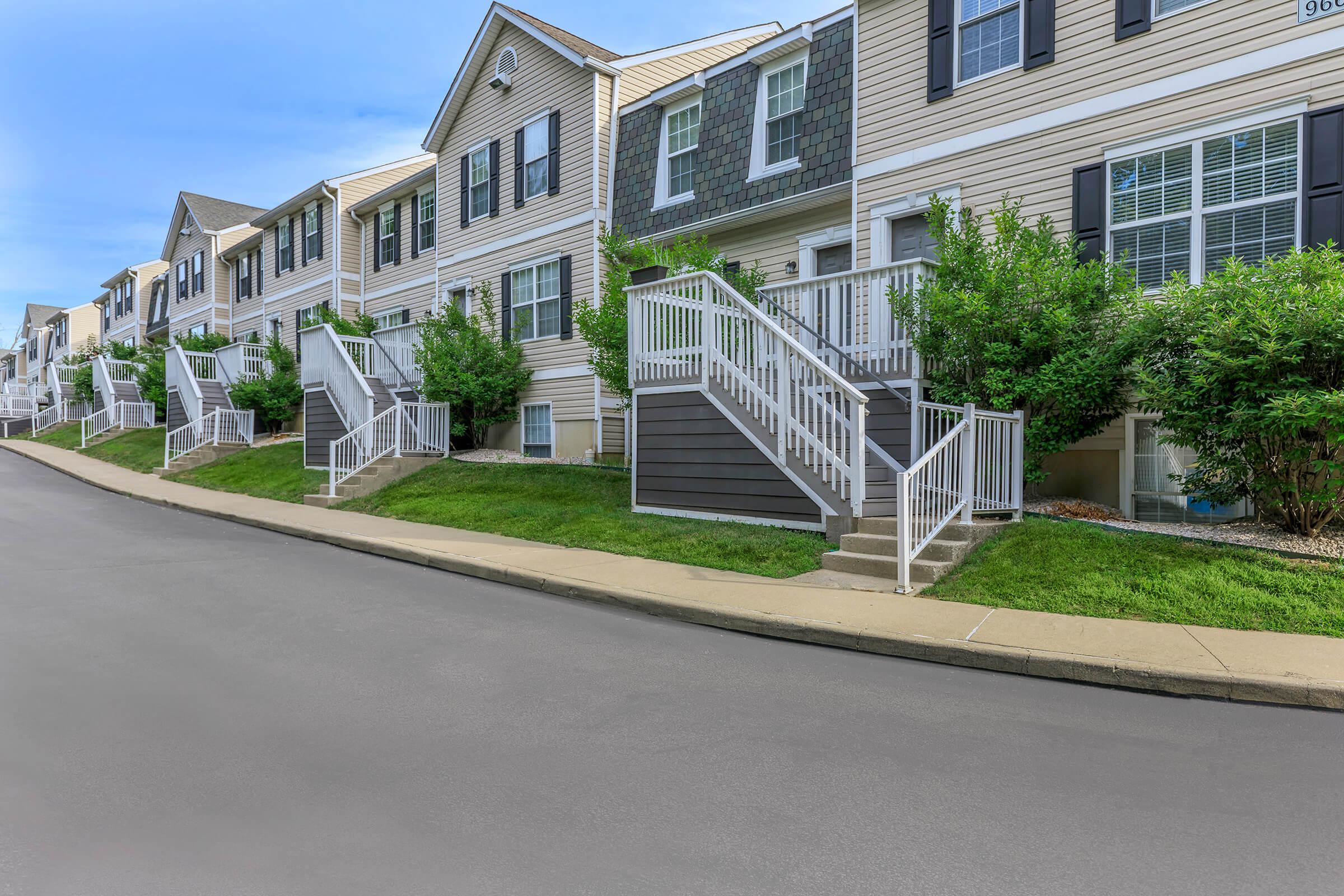 an empty road with grass on the side of a building