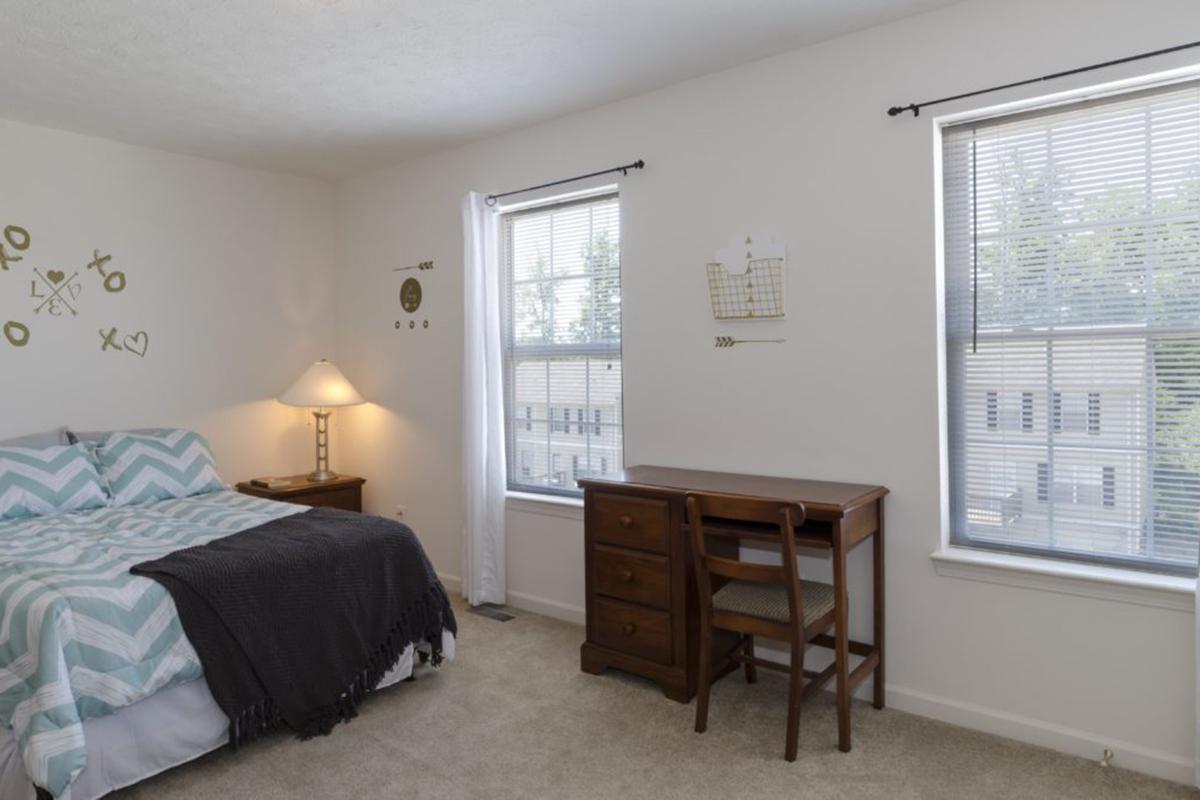 a bedroom with a bed and desk in a room