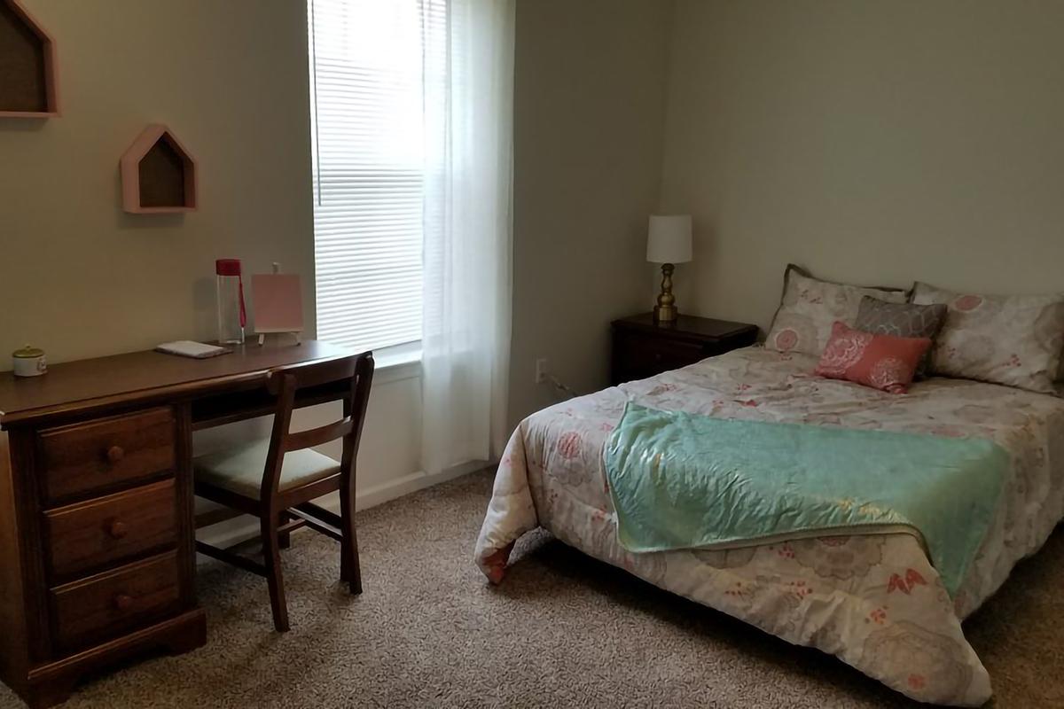 a bedroom with a bed and desk in a room