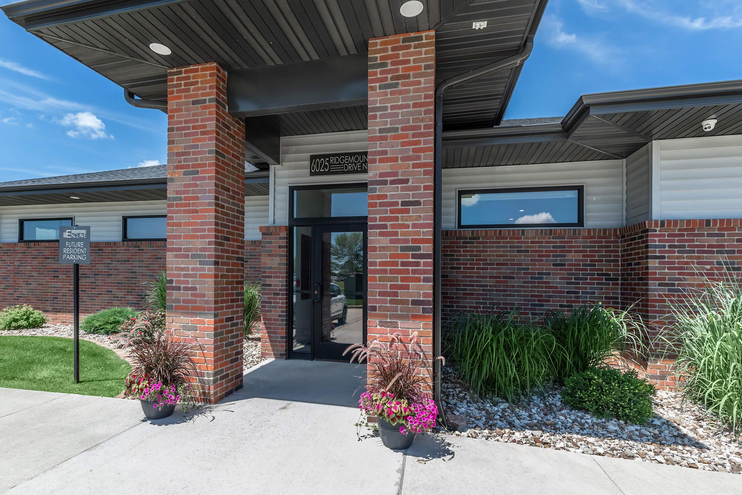 a close up of a flower garden in front of a brick building