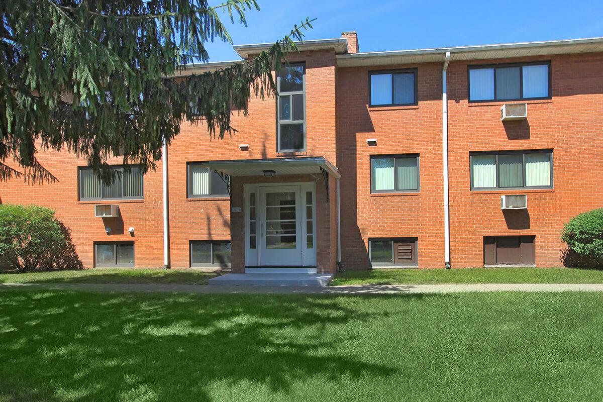 a large brick building with grass in front of a house