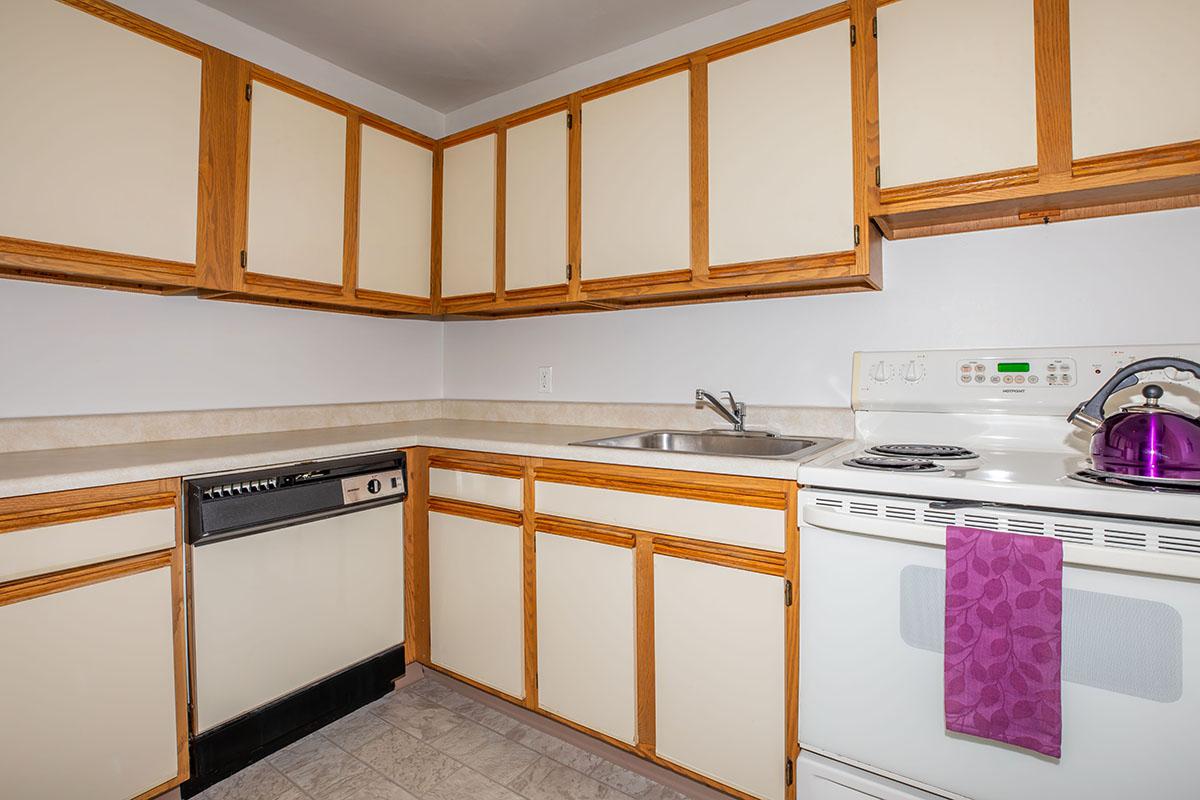 a kitchen with wooden cabinets and a bed