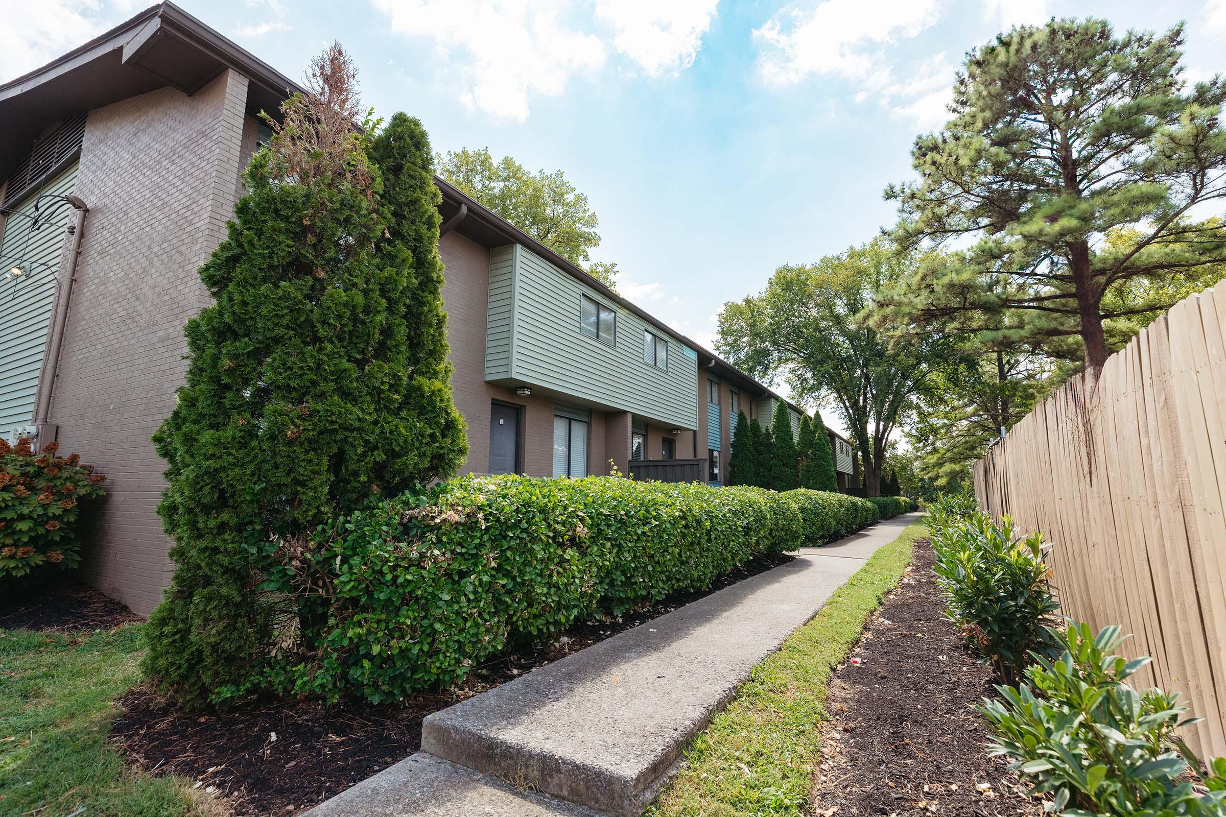 a house with bushes in front of a brick building