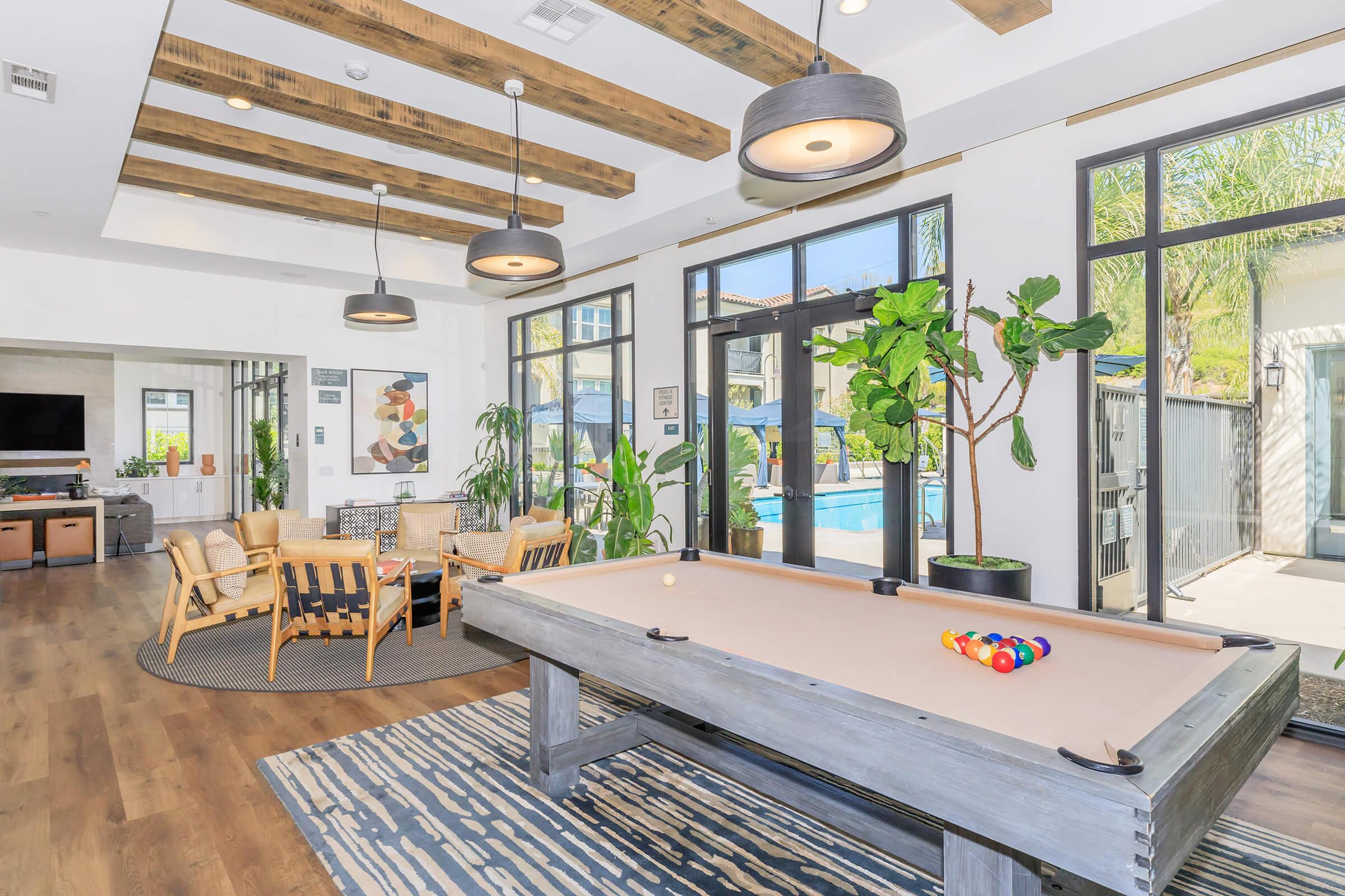 Two-Bedroom Apartments in Riverside, CA - Trails At Canyon Crest - Clubhouse With A Pool Table, Lounge Area, TV, And Large Windows With A Pool View