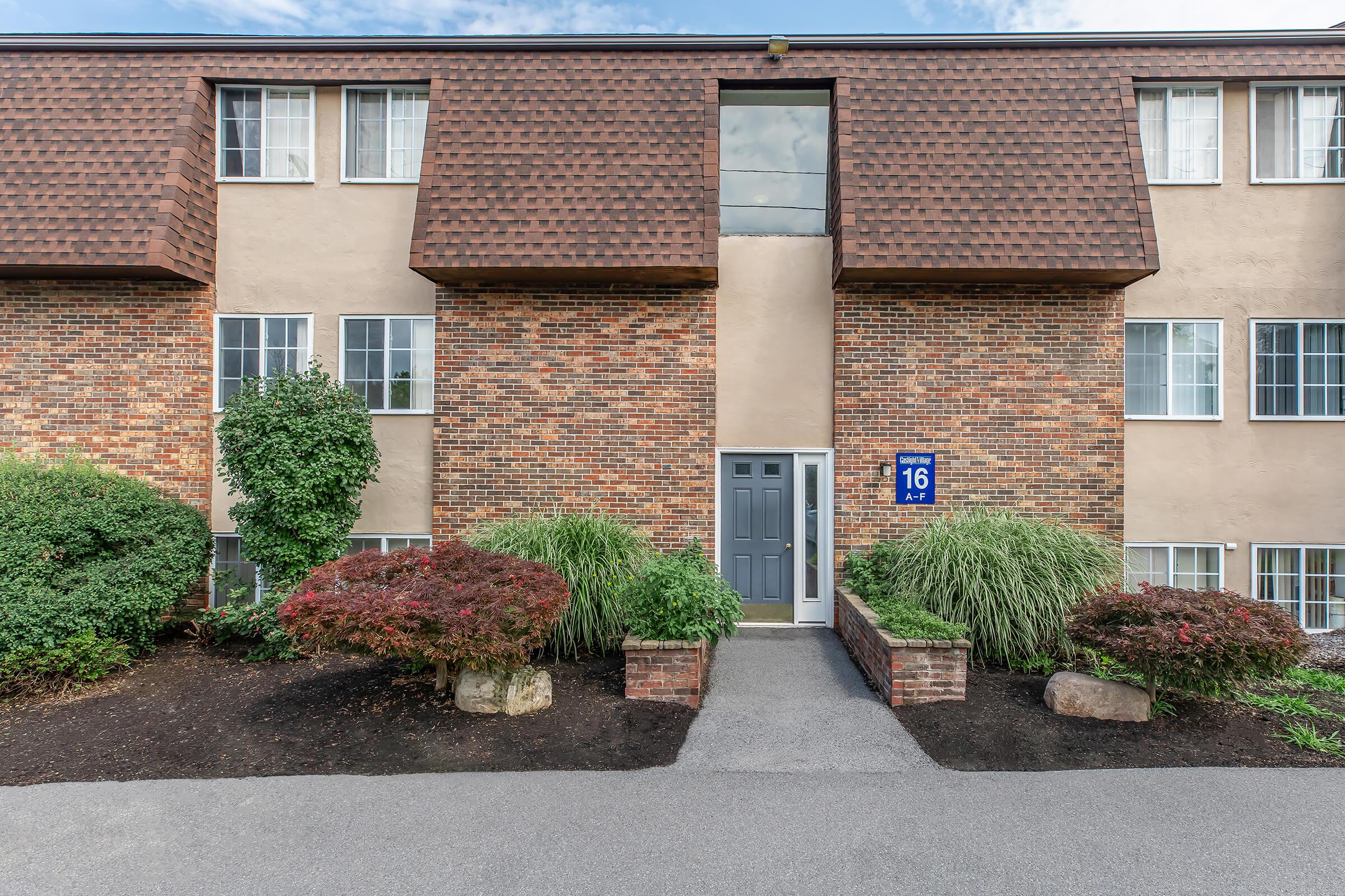 a house with bushes in front of a brick building