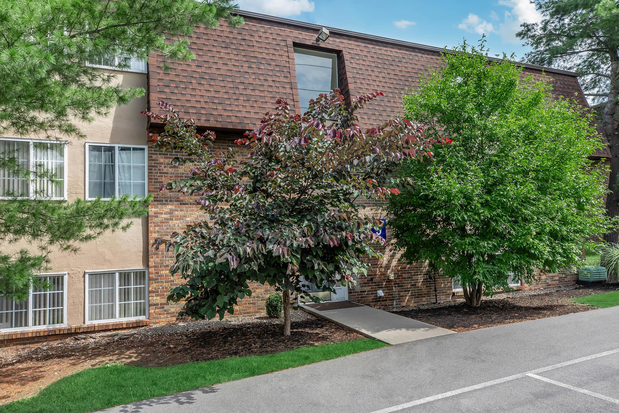 a house with bushes in front of a brick building