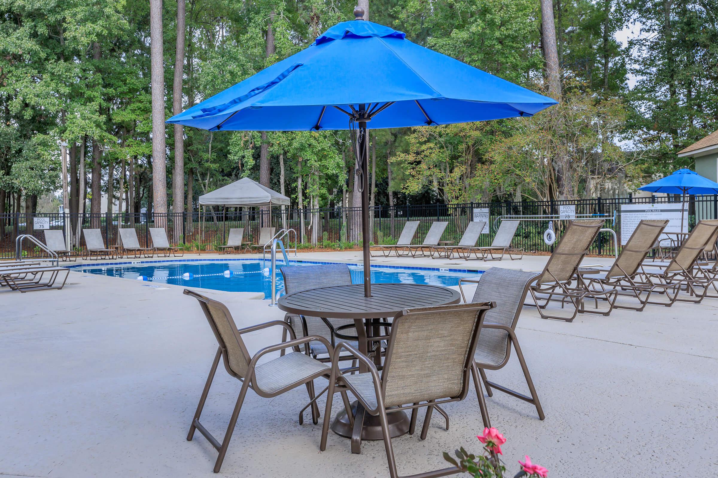 a group of lawn chairs sitting on a table with a blue umbrella